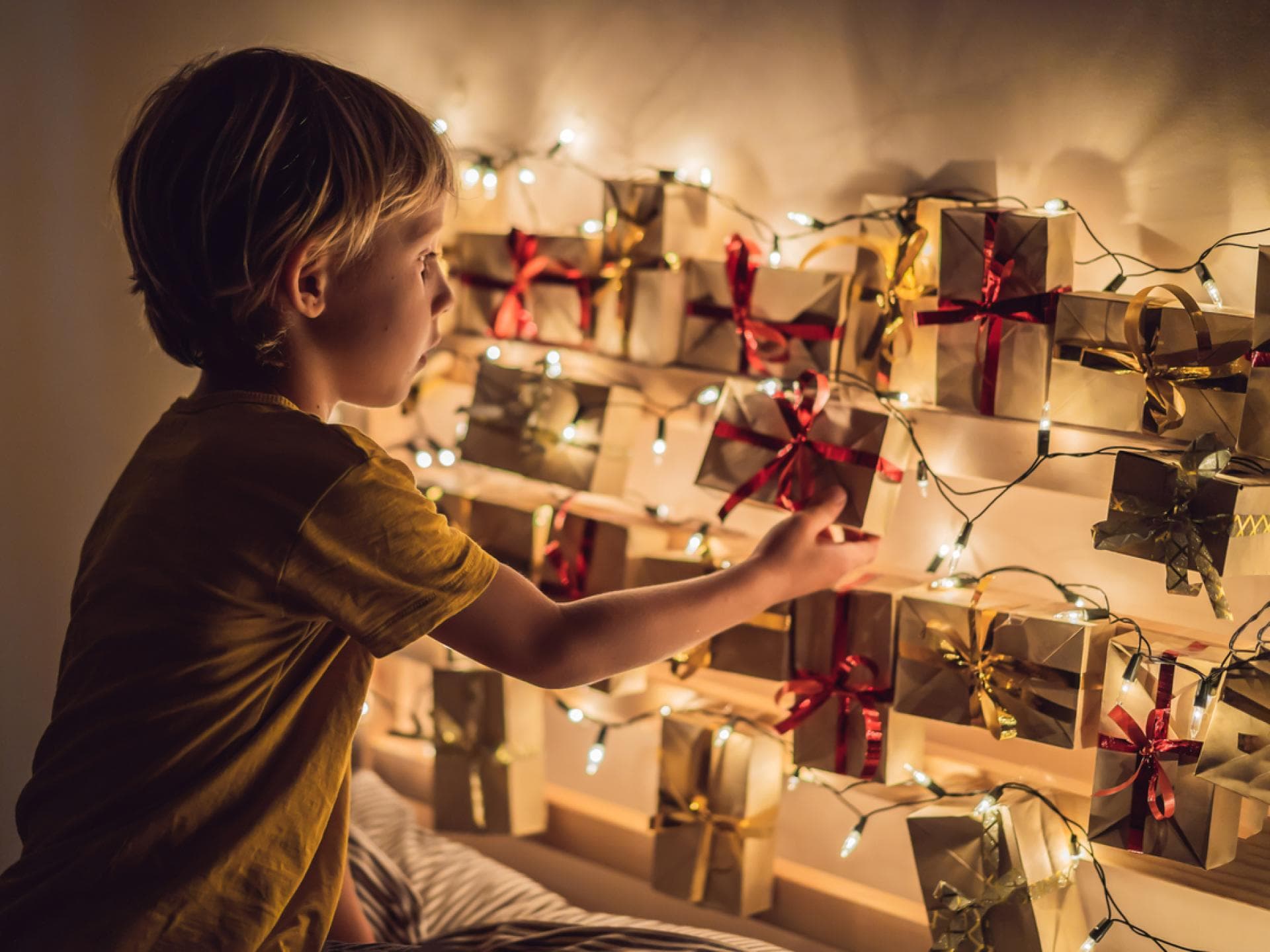 In unserem Adventskalender findet ihr die Weihnachtsgeschichte in 24 Teilen zum Ausdrucken. Ein kleiner Junge öffnet ein Türchen seines Adventskalenders.