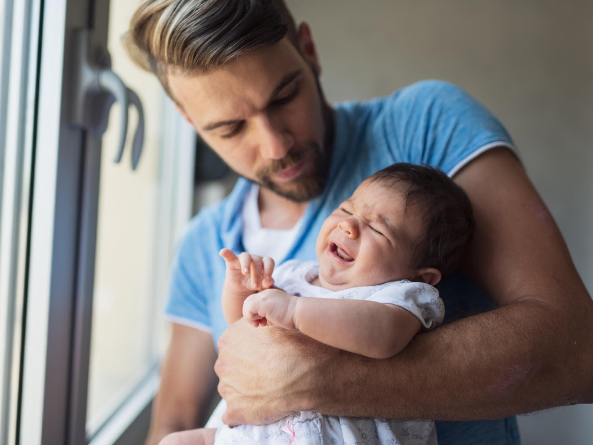 Junger Vater mit Baby auf dem Arm: Papas in Elternzeit müssen sich viele blöde Sprüche anhören.