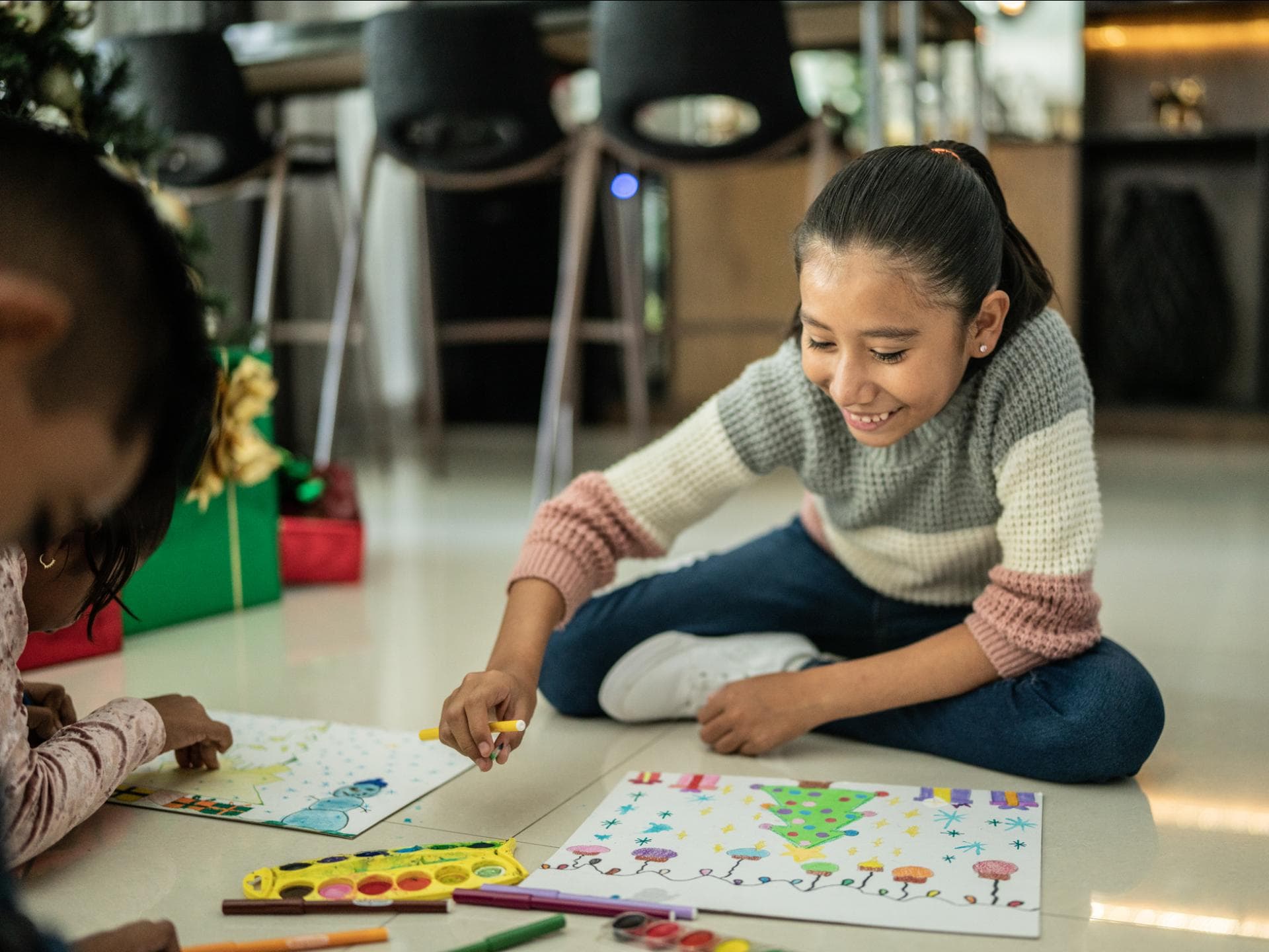 Geschwister malen zusammen Weihnachtsbilder auf dem Boden bunt aus. Geschwister malen zusammen Weihnachtsbilder auf dem Boden bunt aus.