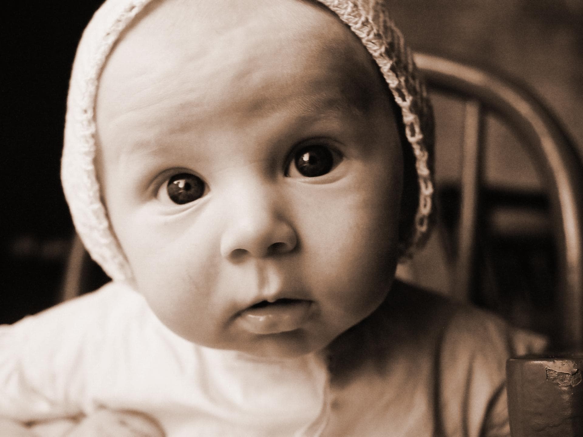 Schwarzweiß-Foto von Baby mit Mützchen.