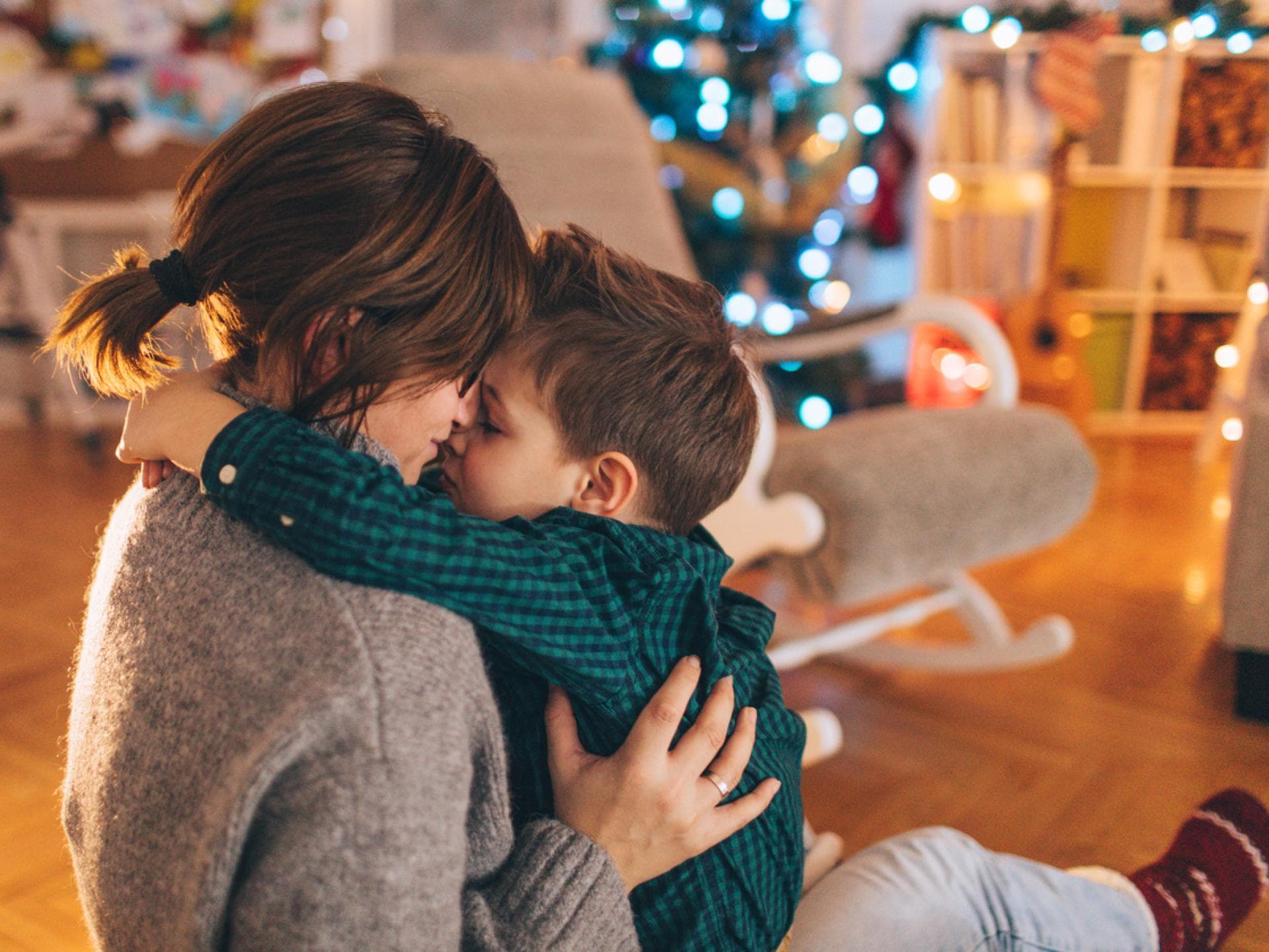 Kleiner Junge kuschelt mit seiner Mama, nachdem sie seine Weihnachtswünsche gelesen hat. Kleiner Junge kuschelt mit seiner Mama, nachdem sie seine Weihnachtswünsche gelesen hat.