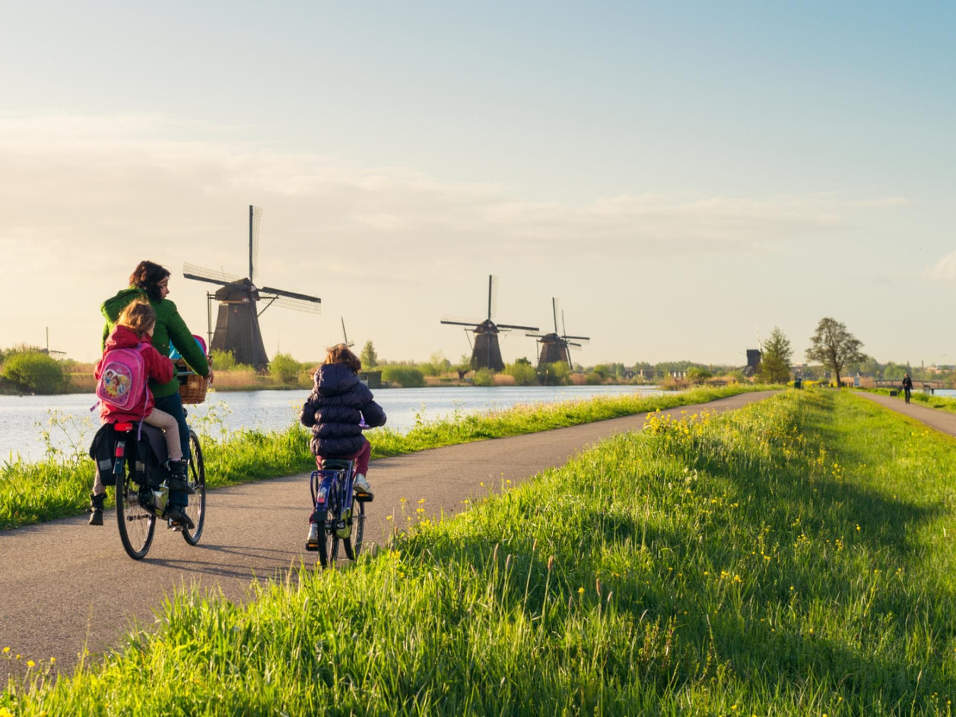 Holländische Familie fährt Fahrrad entlang von niederländischen Windmühlen. Holländische Familie fährt Fahrrad entlang von niederländischen Windmühlen.