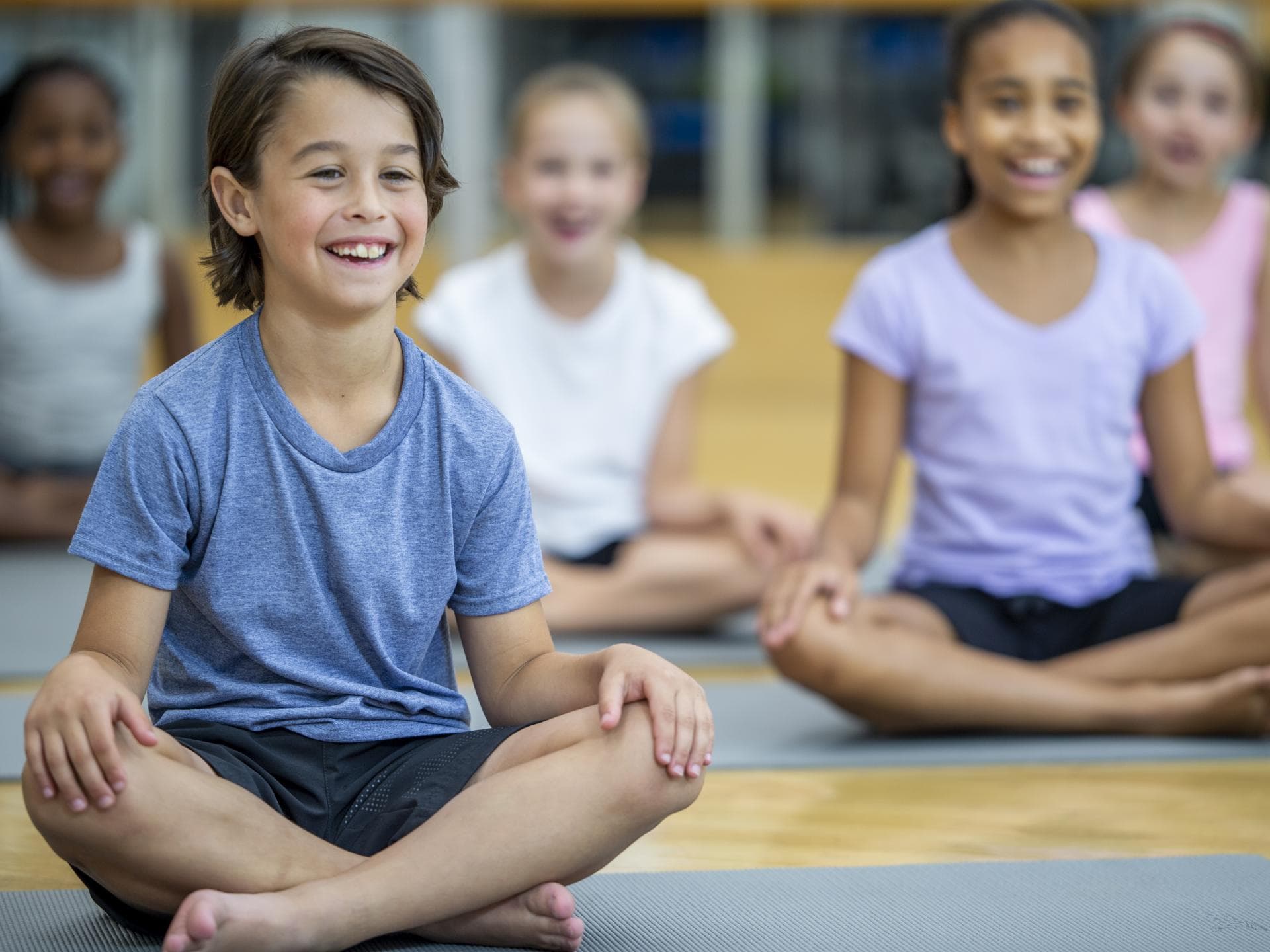 Fröhliche Kinder sitzen in der Schule auf Yogamatten. Fröhliche Kinder sitzen in der Schule auf Yogamatten.