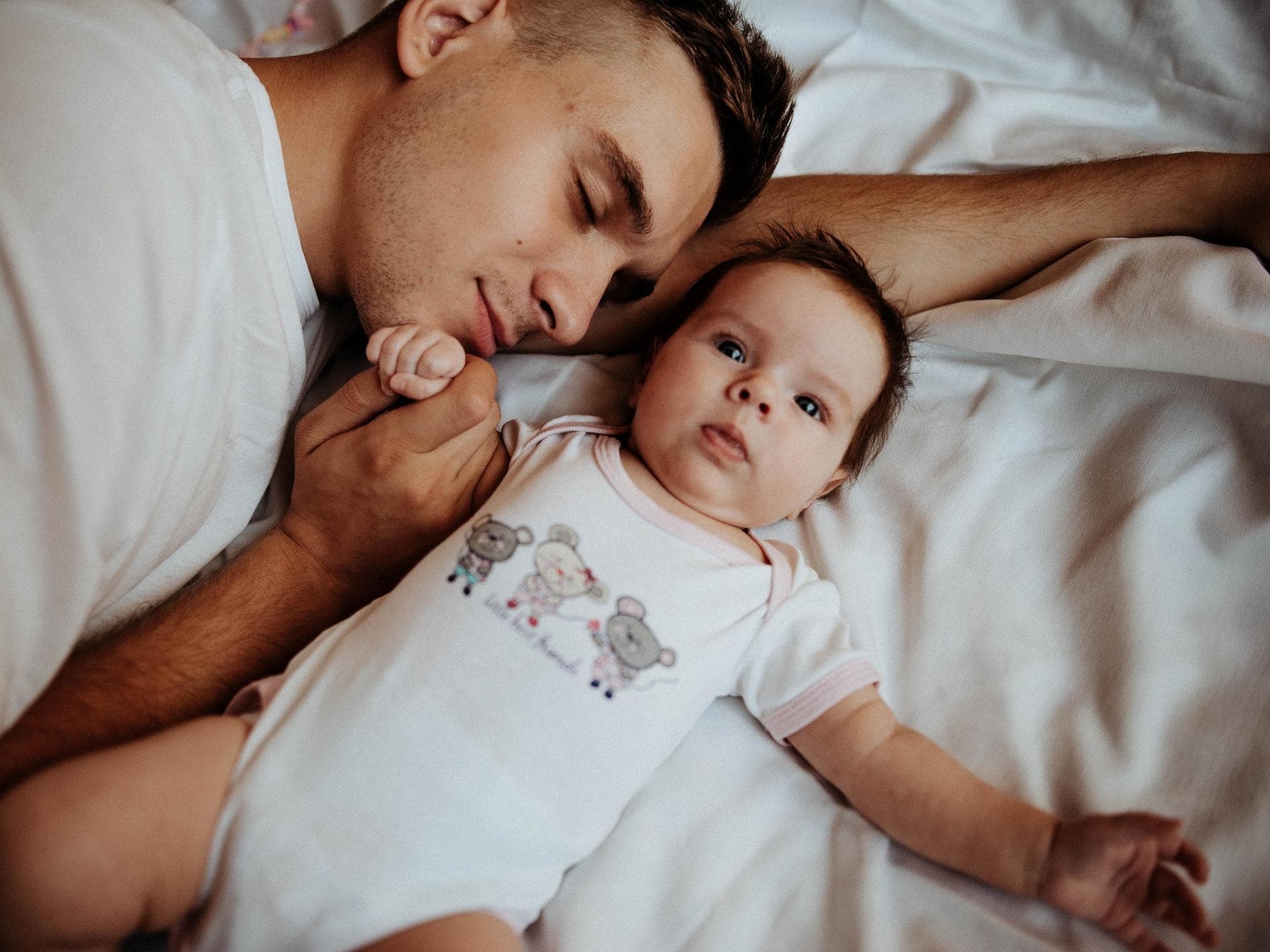 Papa hält beim Schlafen die Hand seines Babys. 