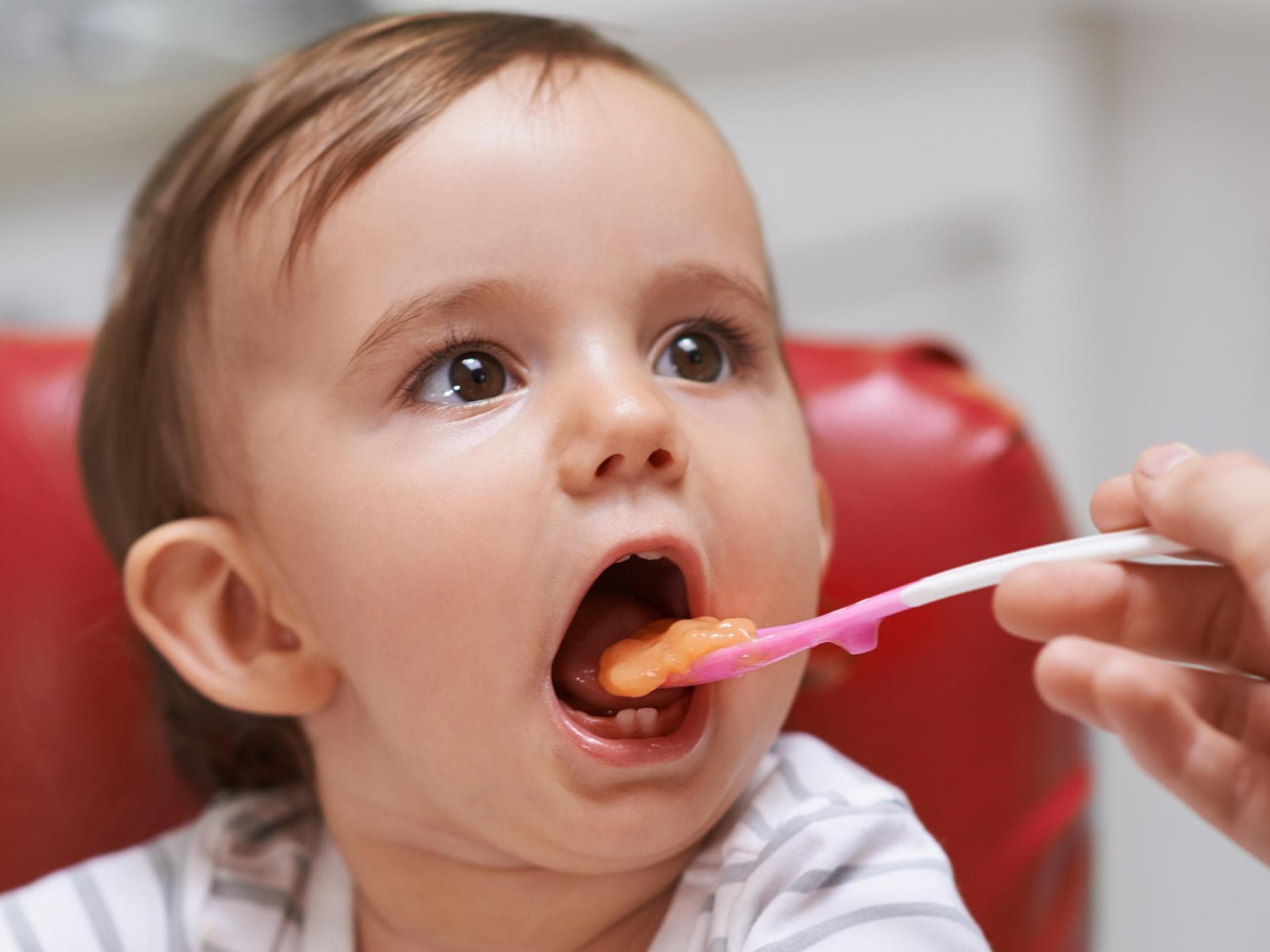 Ein kleines Kind isst einen Löffel Brei aus einem Babygläschen. Ein kleines Kind isst einen Löffel Brei aus einem Babygläschen.