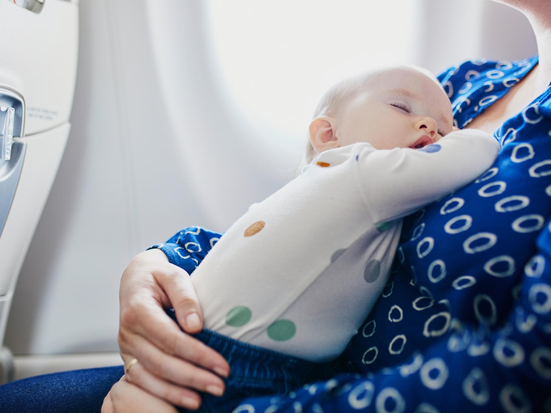 Ein kleines Baby schläft im Flugzeug auf dem Schoß seiner Mutter. Ein kleines Baby schläft im Flugzeug auf dem Schoß seiner Mutter.