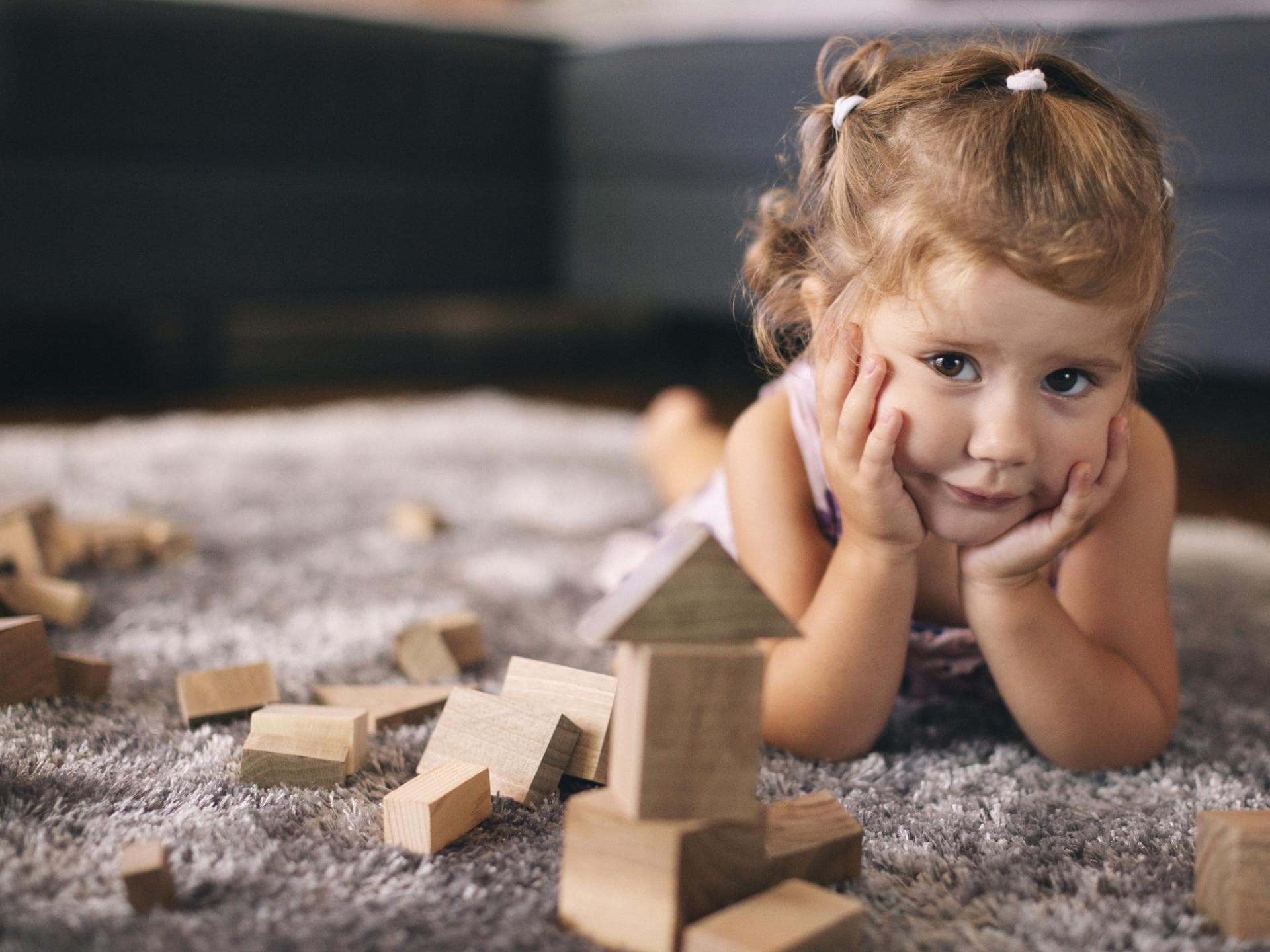 Holzspielzeug kommt nicht bei allen Kindern gut an. Kleines Mädchen spielt mit Holzbauklötzen.