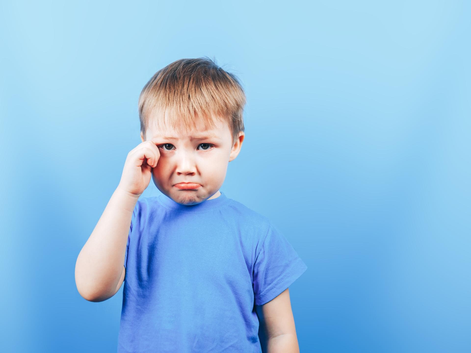 Kleiner Junge mit Schmollmund, reibt sich das Auge.