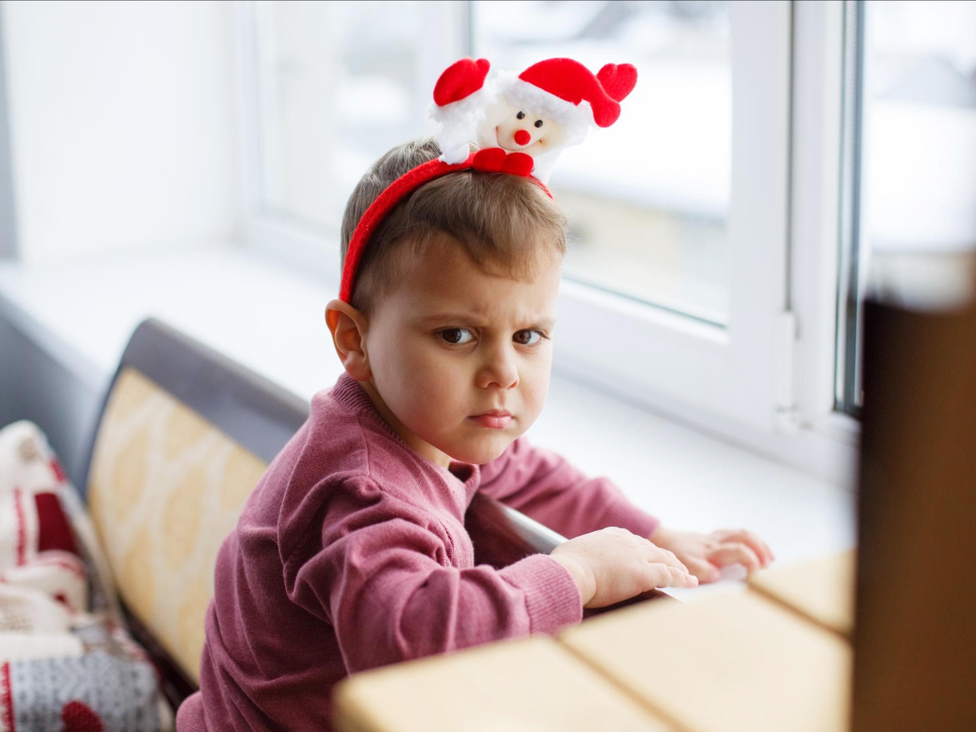 Ein Kind mit Weihnachtsmannhaarreif, der sauer gut