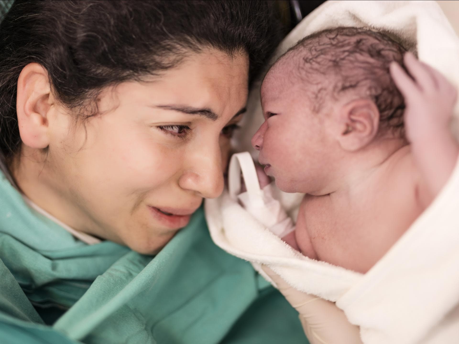 Eine frisch gebackene Mutter weint als sie ihr Baby endlich neben sich liegen hat. Eine frisch gebackene Mutter weint als sie ihr Baby endlich neben sich liegen hat.