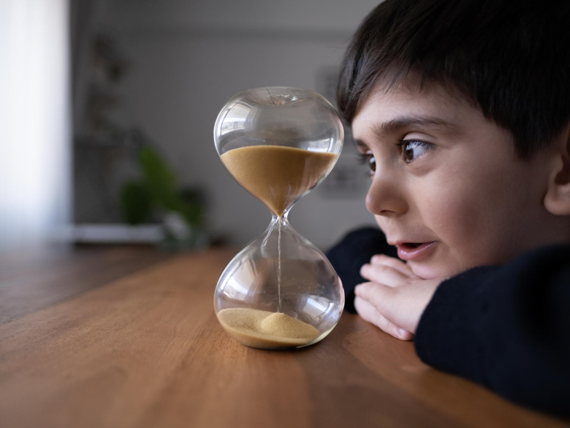 Kleiner Junge schaut auf die Sanduhr: Mama hat einen Timer gestellt. Kleiner Junge schaut auf die Sanduhr: Mama hat einen Timer gestellt.