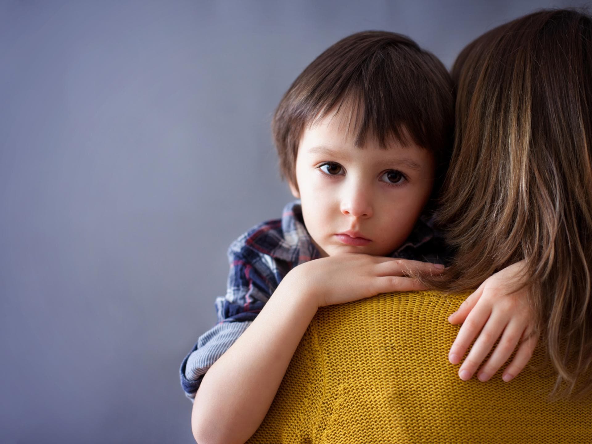 Unglücklichsein gehört zum Heranwachsen dazu. Unglücklicher Junge umarmt seine Mutter.