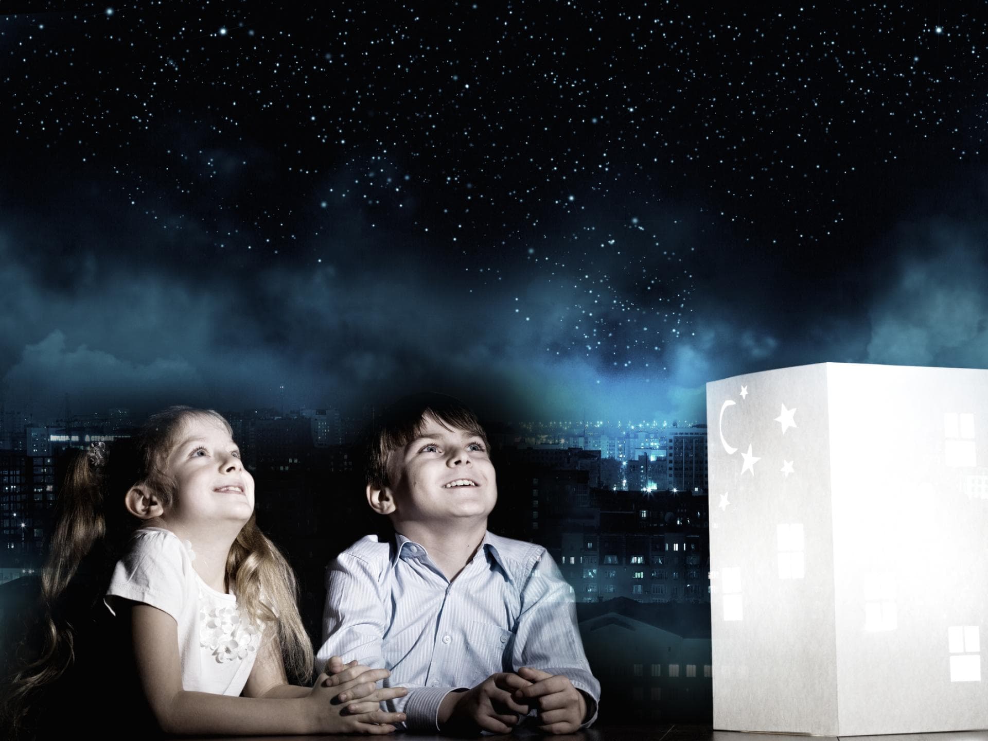 Ein Junge und ein Mädchen starren begeistert in den projizierten Sternenhimmel im Zimmer.