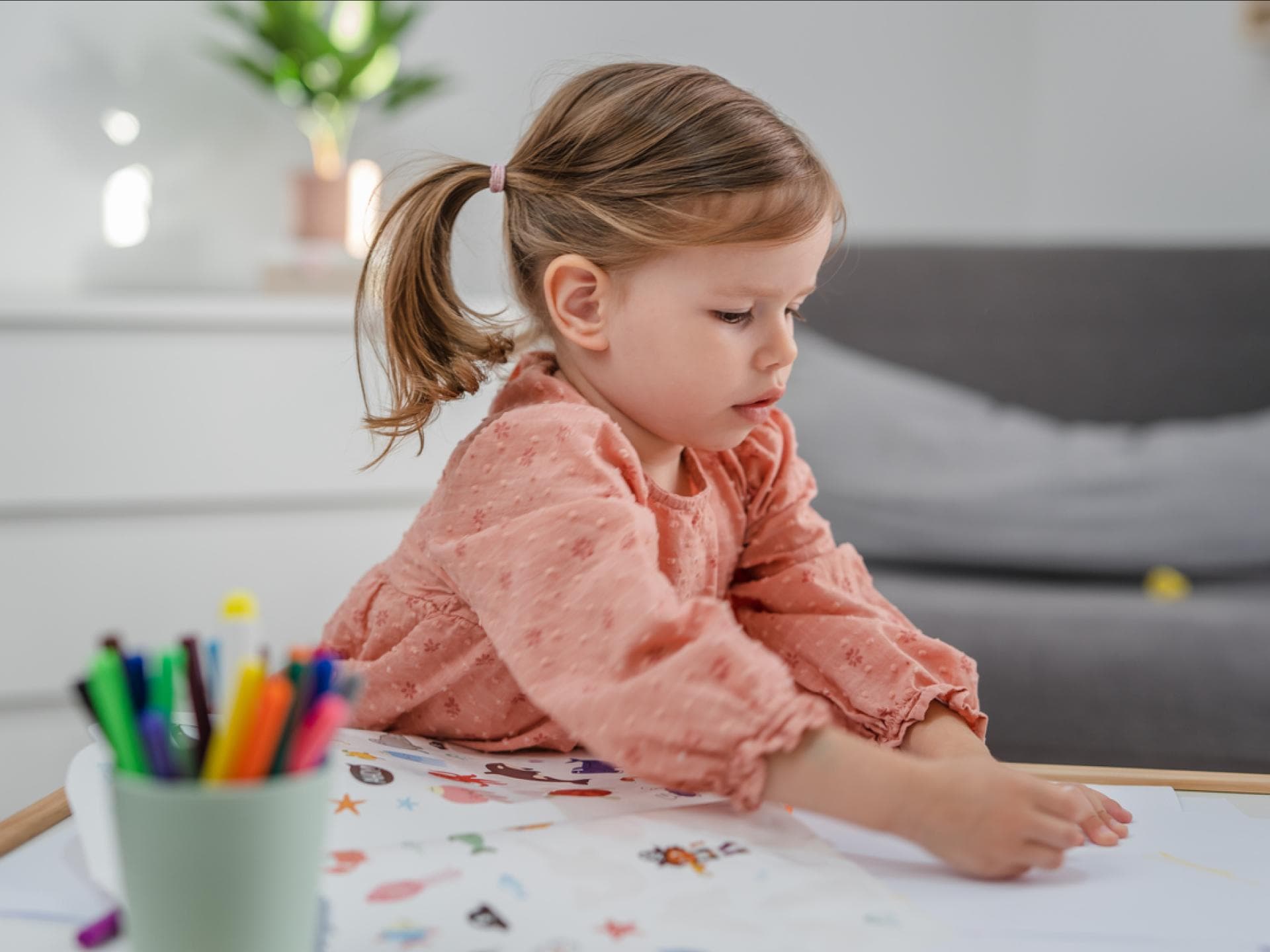 Kleines Mädchen klebt Sticker auf.