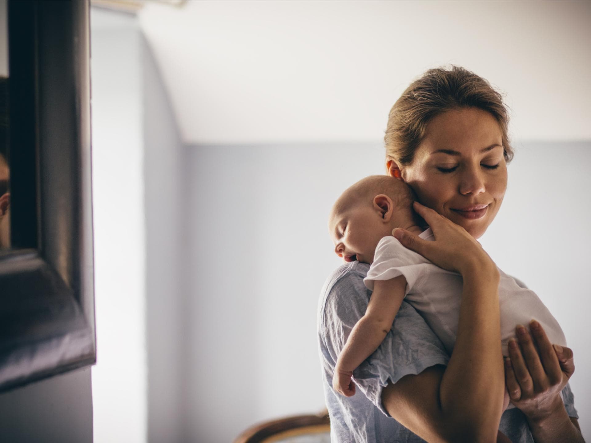 Mama trägt ihr Baby liebevoll im Arm.
