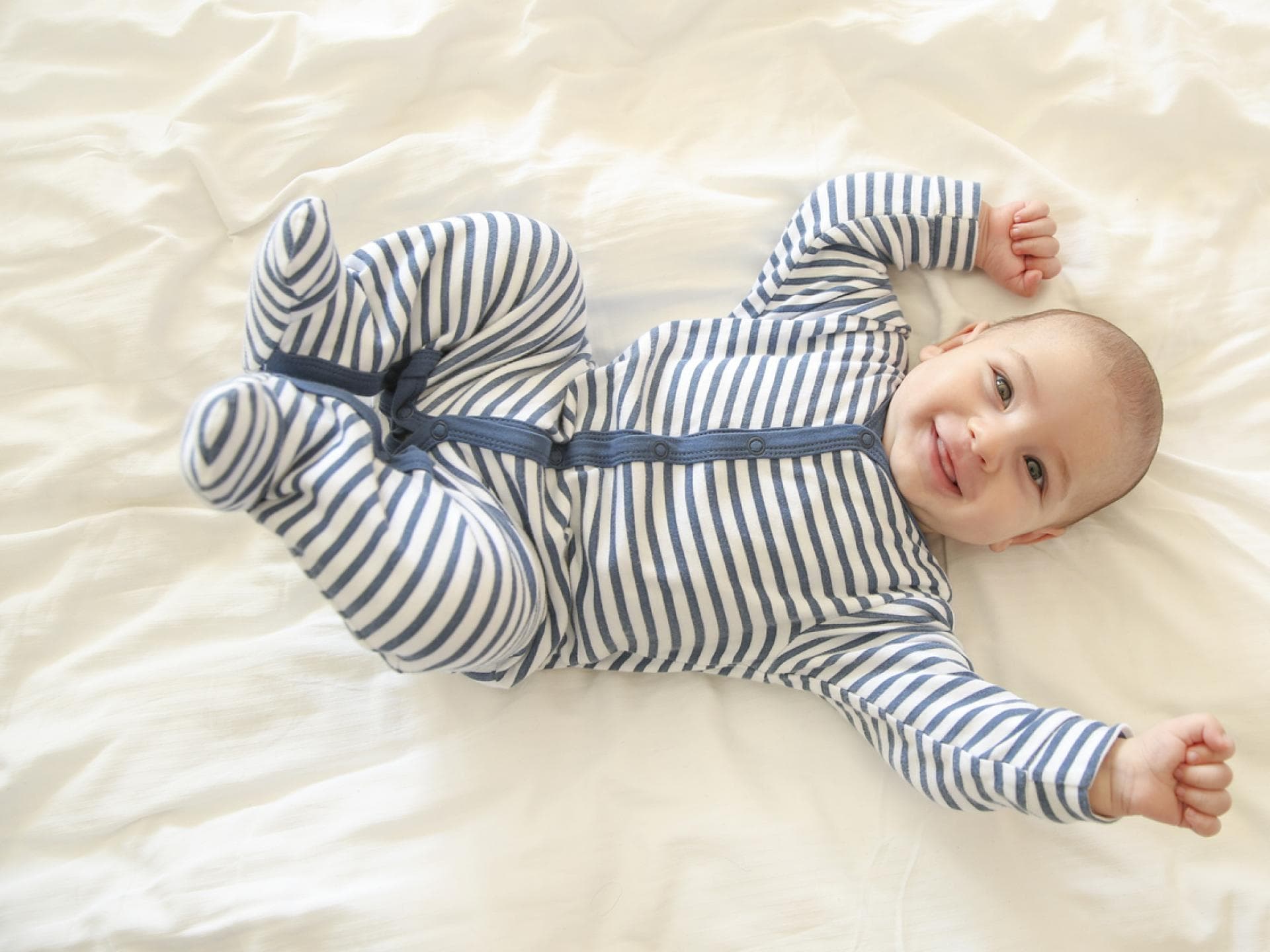 Baby-Junge in einem Strampler hat gute Laune und lacht.