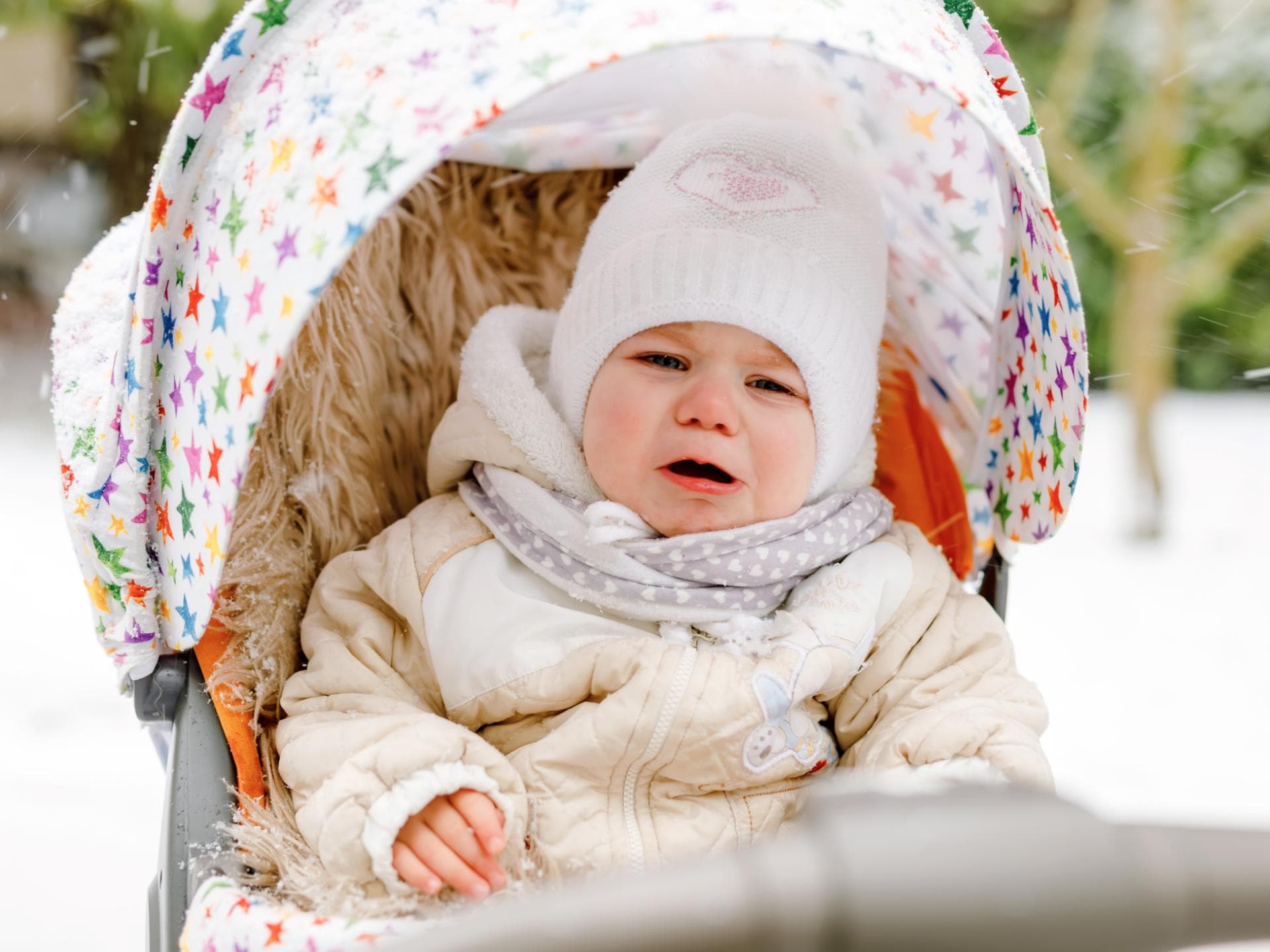 Ein Kleinkind ohne Handschuhe weint im Buggy im Winter.