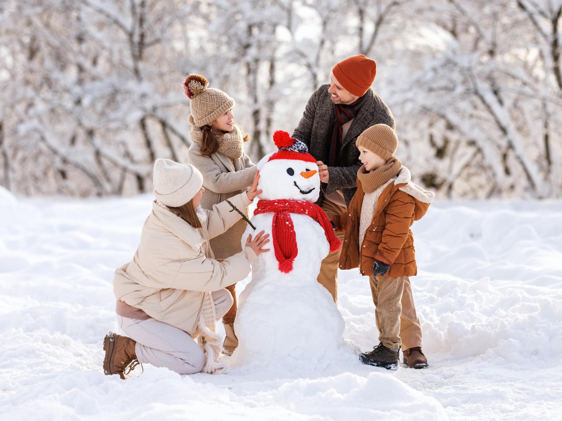 Eine vierköpfige Familie baut einen Schneemann.