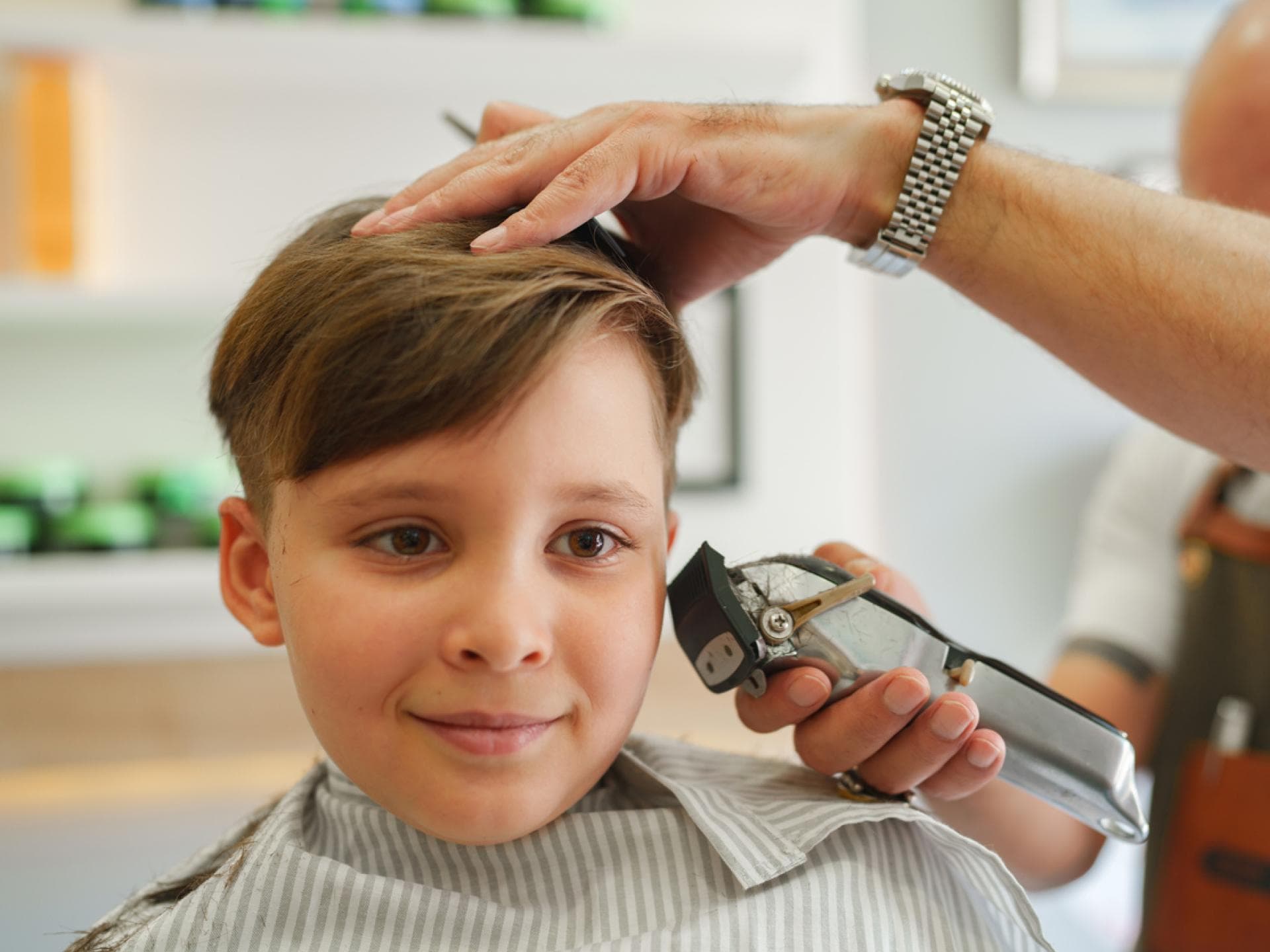 Ein Junge, der beim Friseur sitzt. 
