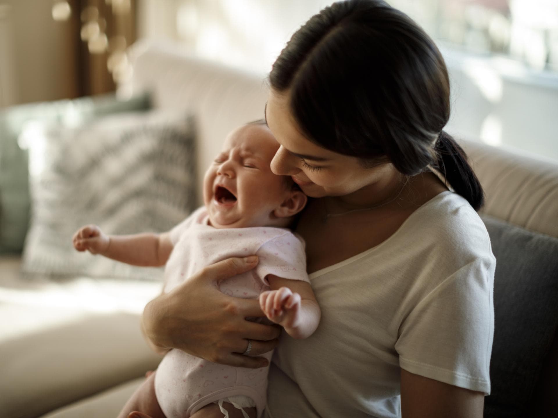 Mama hält zitterndes Baby im Arm.