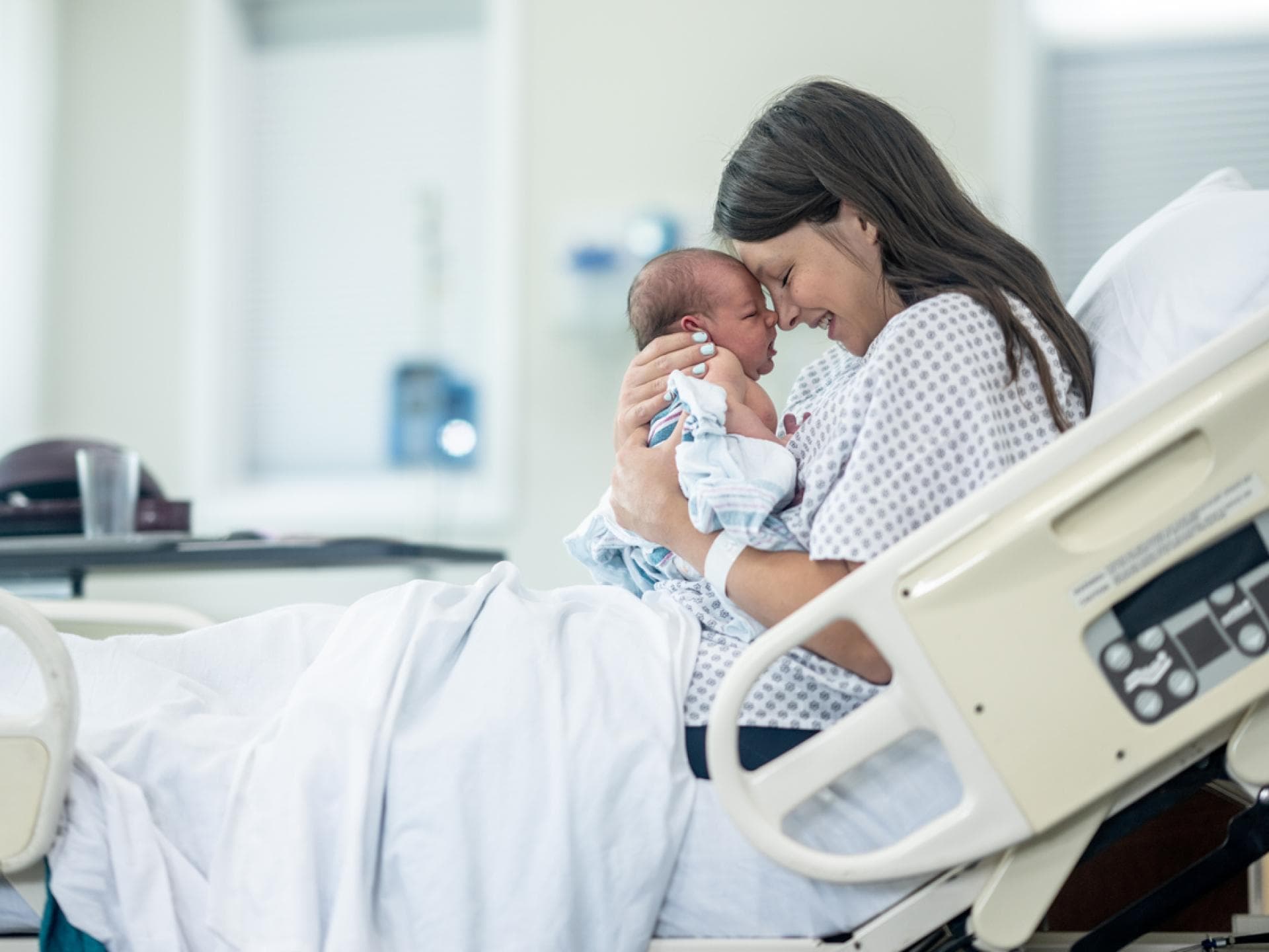 Mama hält ihr Neugeborenes glücklich im Arm.