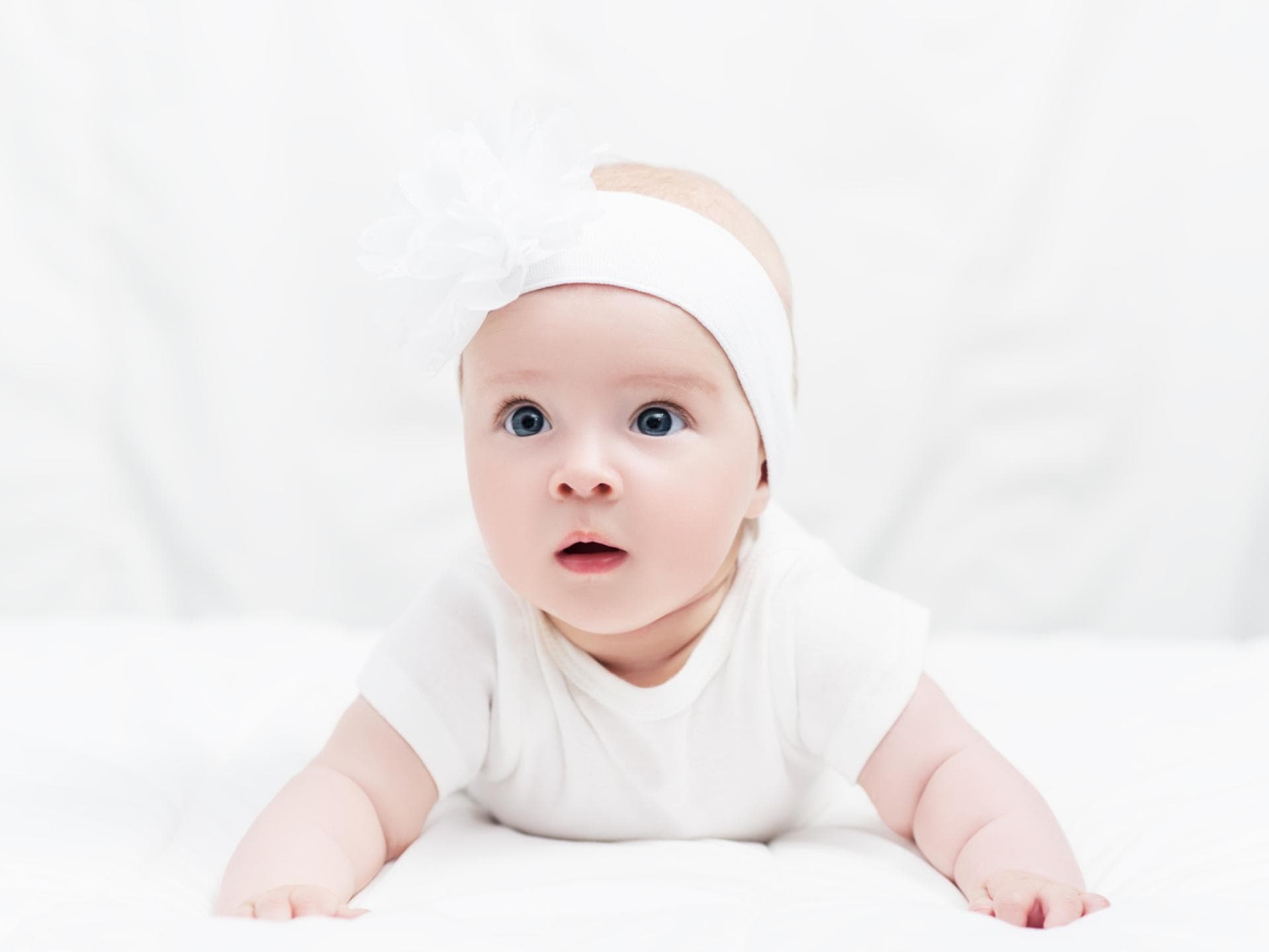 Baby in Bauchlage mit niedlichem Kopfband. Baby in Bauchlage mit niedlichem Kopfband.