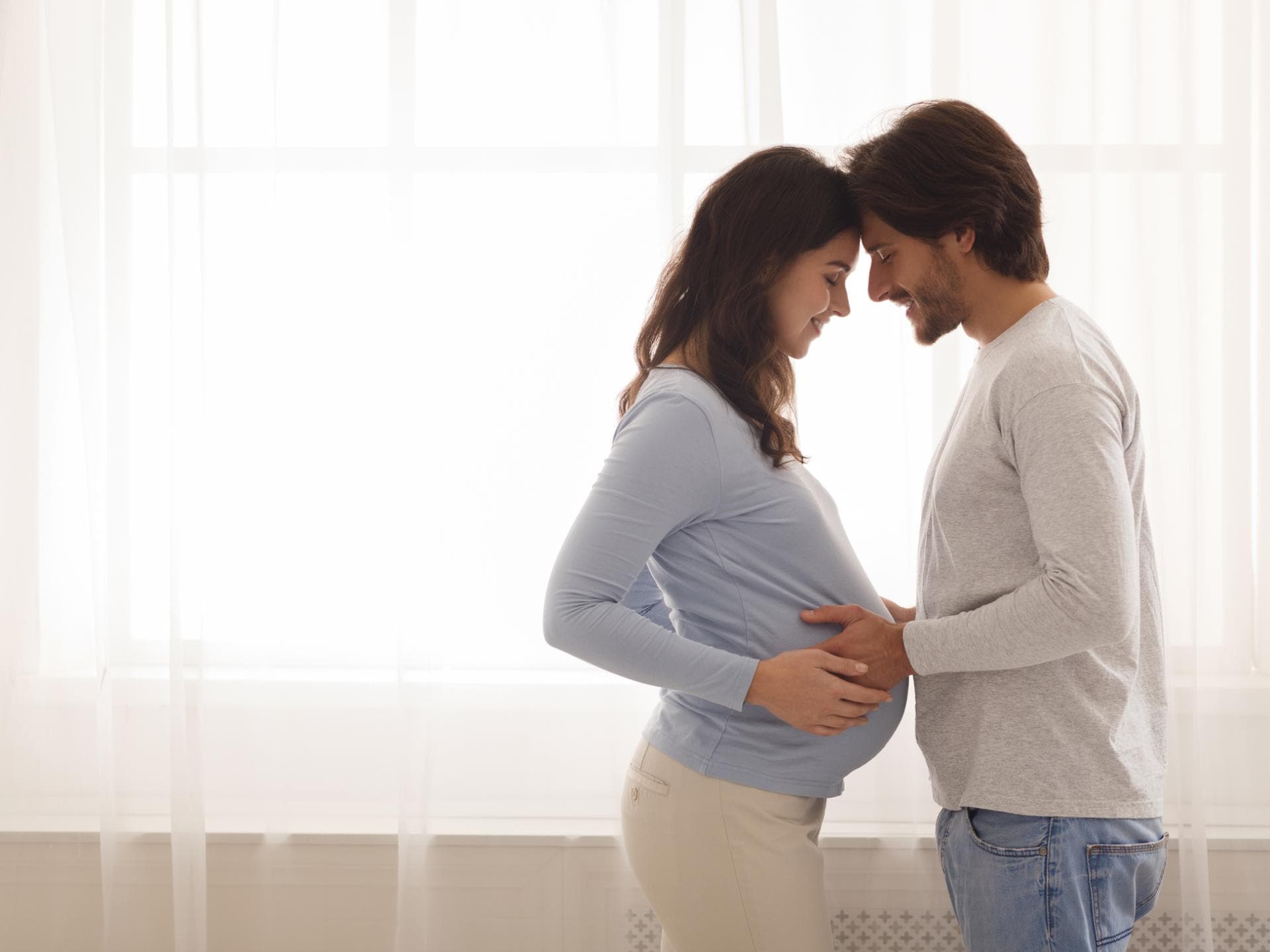 Bevor das Kind kommt, sollten sich Eltern zwei wichtige Fragen stellen. Schwangere Frau und Mann umarmen sich.