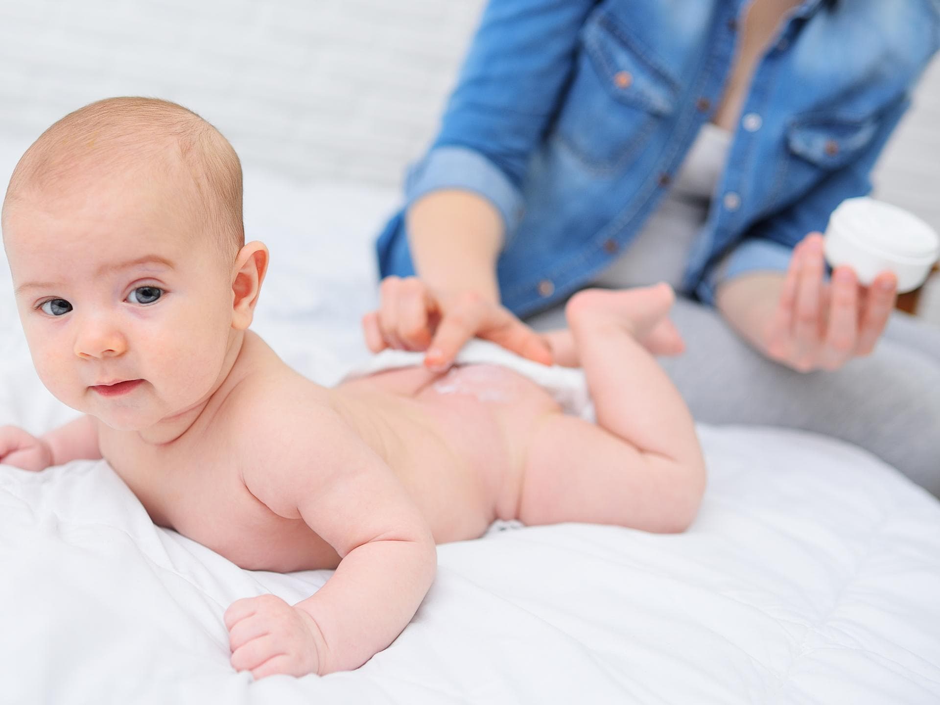 Eine Mama cremt ihrem Baby den Po ein.