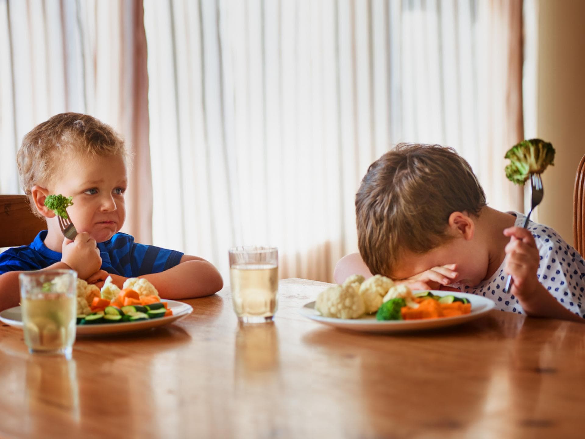 Kinder von Gemüse zu begeistern, ist oft nicht ganz einfach. Unglückliche Kinder am Esstisch.
