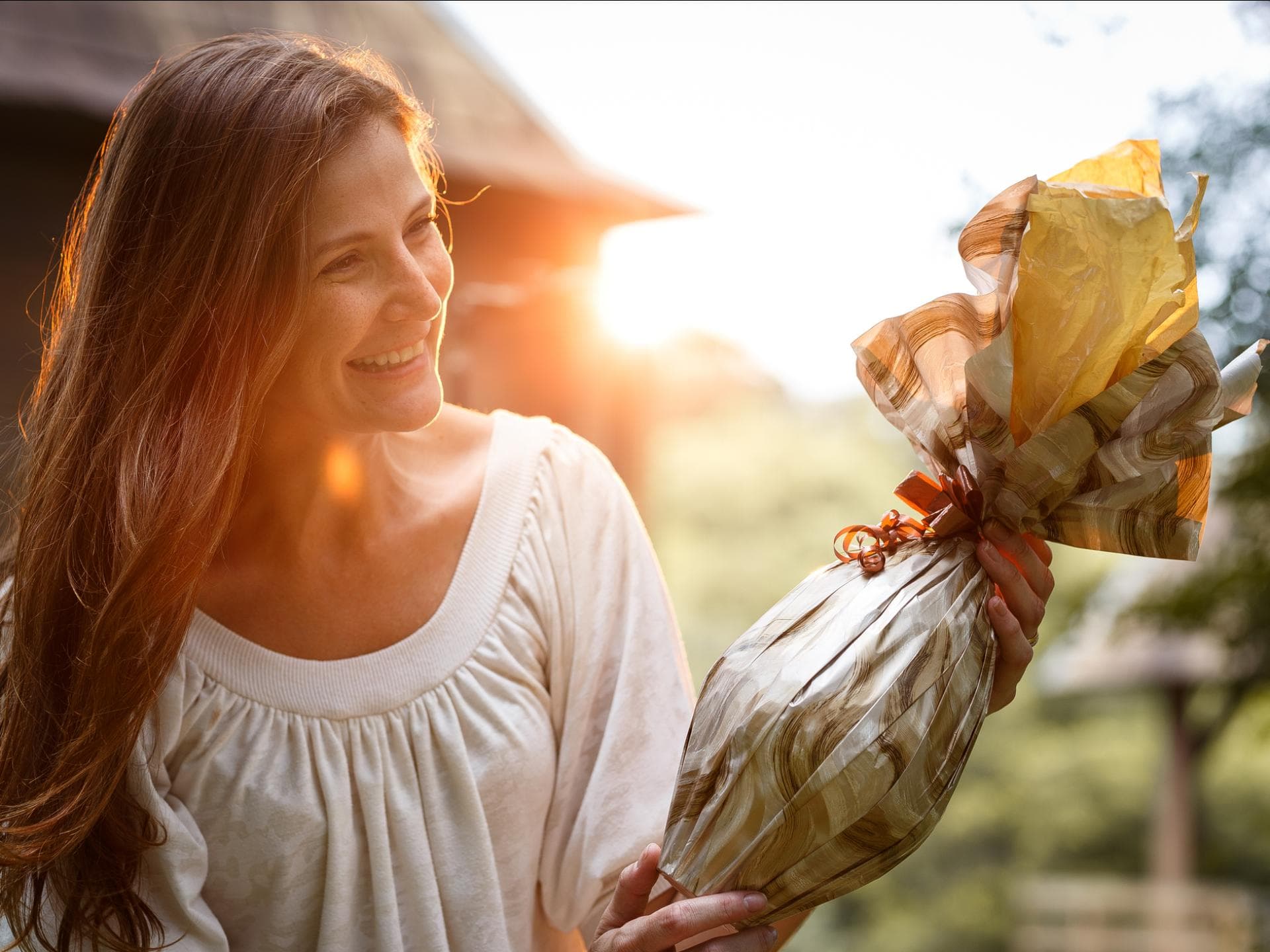 Eine Frau bekommt ein Ostergeschenk überreicht und freut sich.