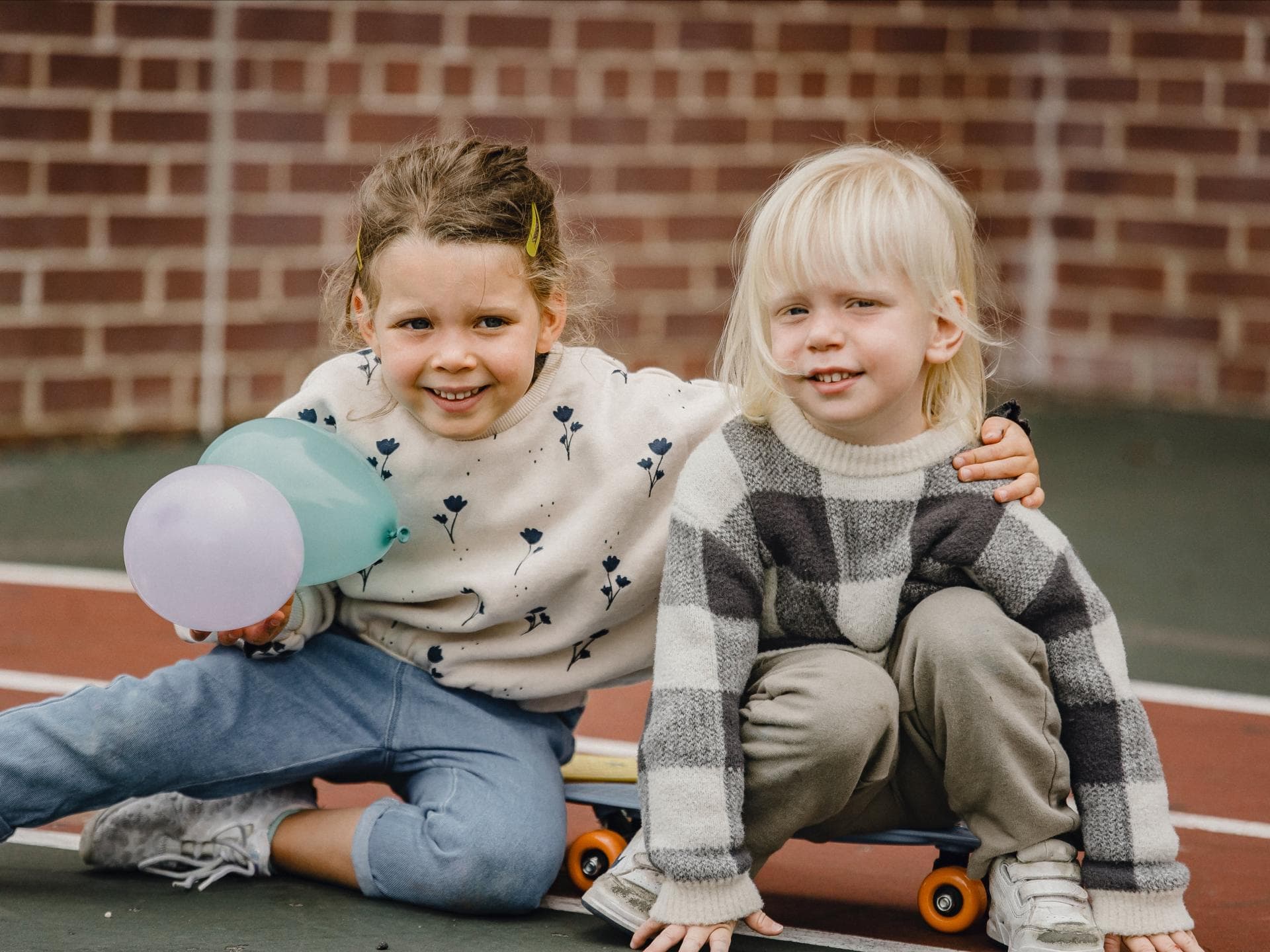 Ein Mädchen und ein Junge auf einem Skateboard draußen