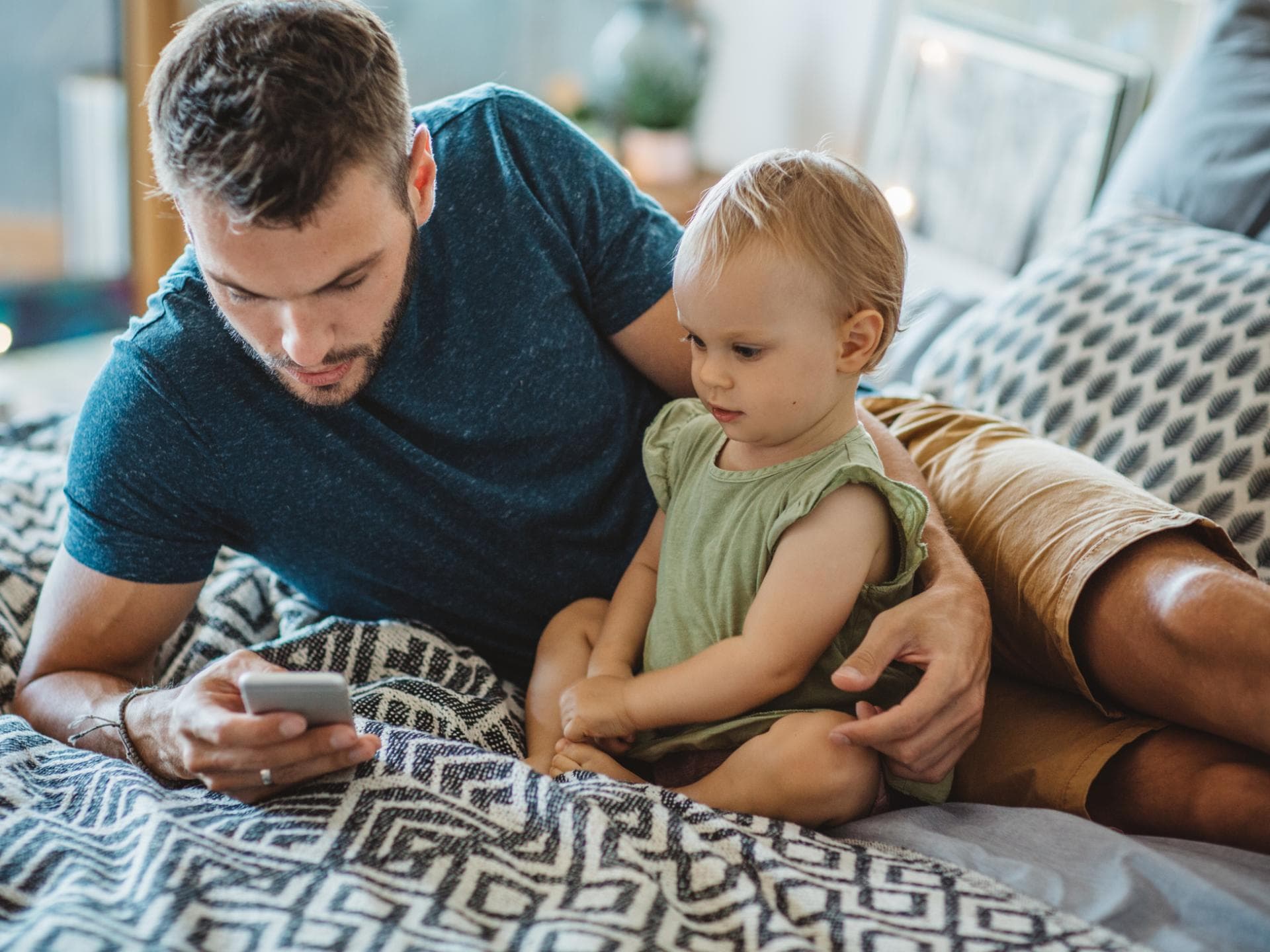 Wenn Eltern ständig vom Handy abgelenkt sind, spricht man von Phubbing. Vater sitzt neben seiner Tochter und guckt aufs Handy