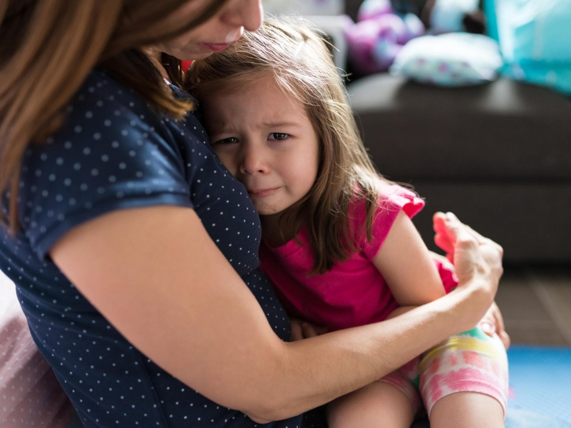Mutter tröstet ihre kleine Tochter und hält sie im Arm.