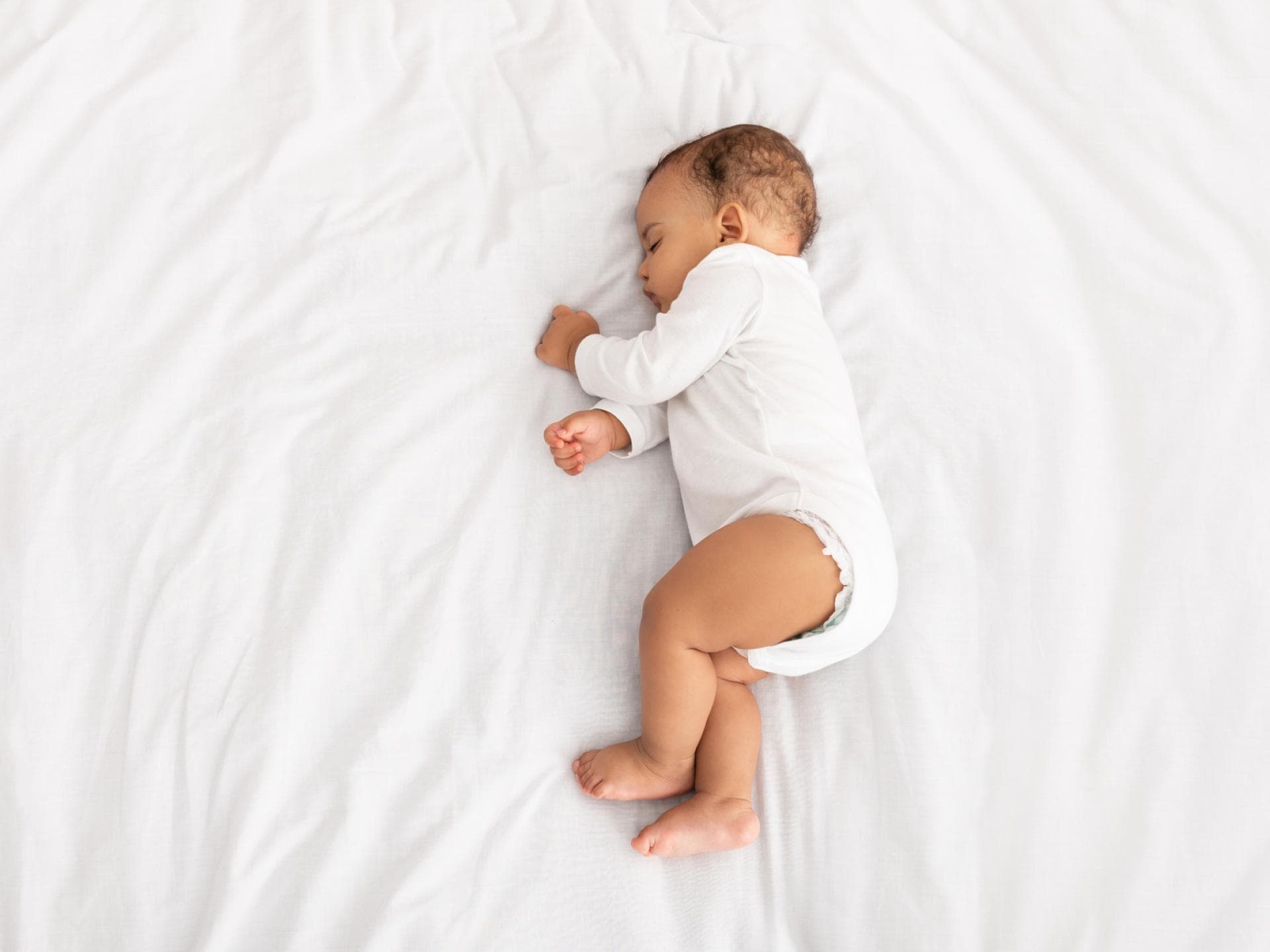 Baby liegt schlafend auf der Seite im Bett