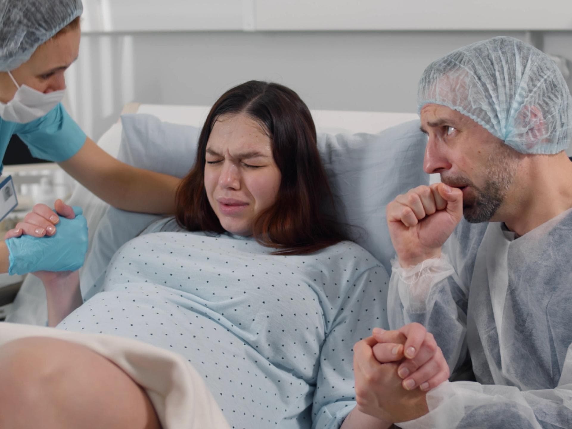 Verängstigter Ehemann, der im Kreißsaal die Hand einer Frau hält