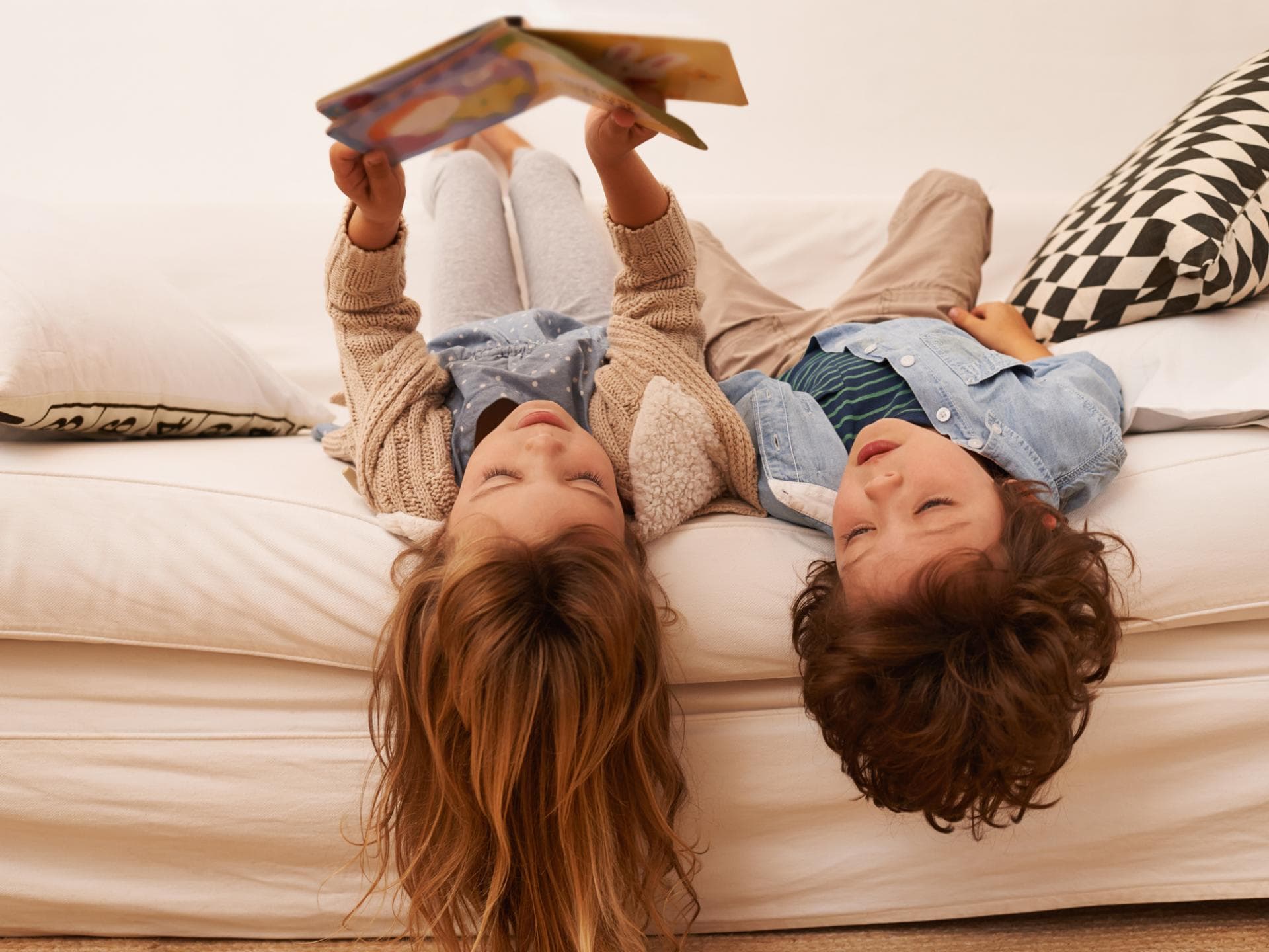 Auf der Leipziger Buchmesse wählte eine Kinder-Jury die besten Bilderbücher aus. Zwei Kinder liegen auf dem Sofa und lesen.