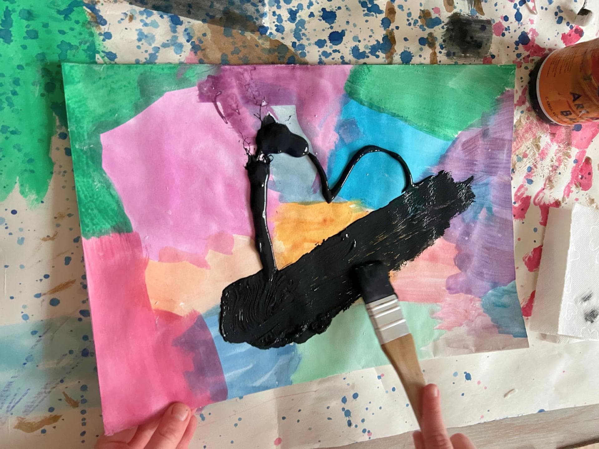 Bunt getuschtes Papier wird mit einer schwarzen Schicht Acrylfarbe übermalt