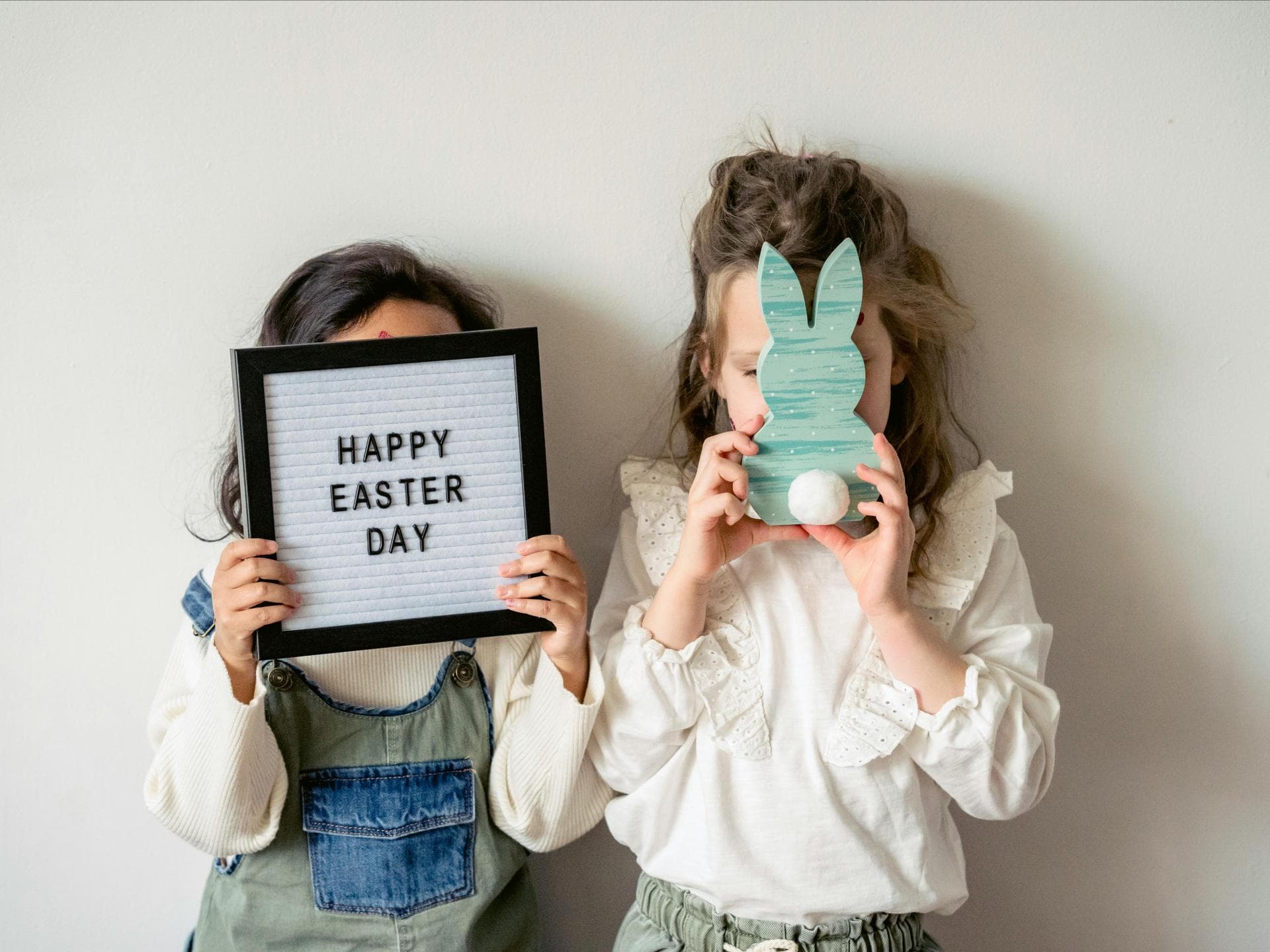 Zwei Mädchen halten zwei Oster-Schilder hoch 