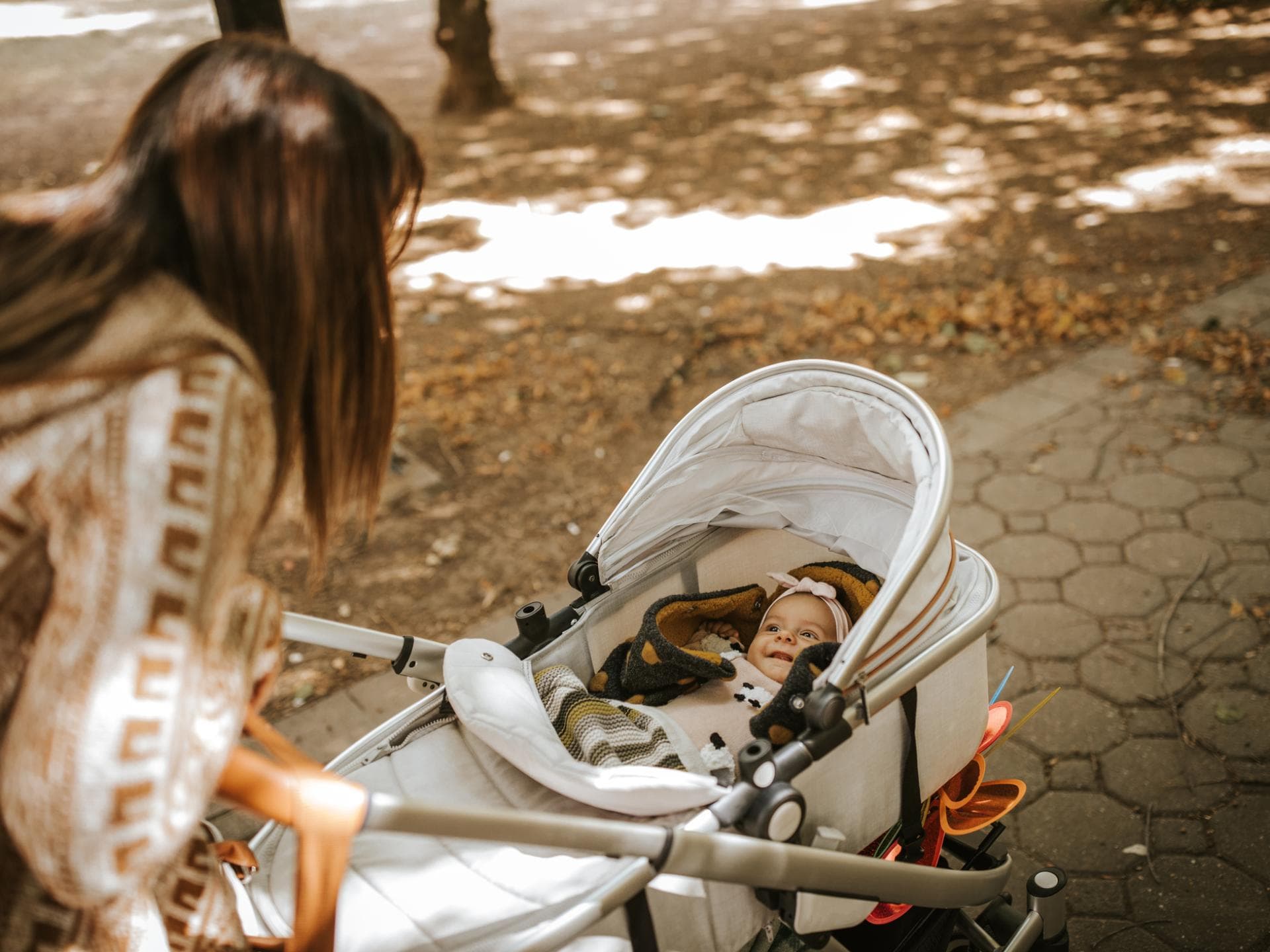 Mutter schiebt Baby im Kinderwagen.