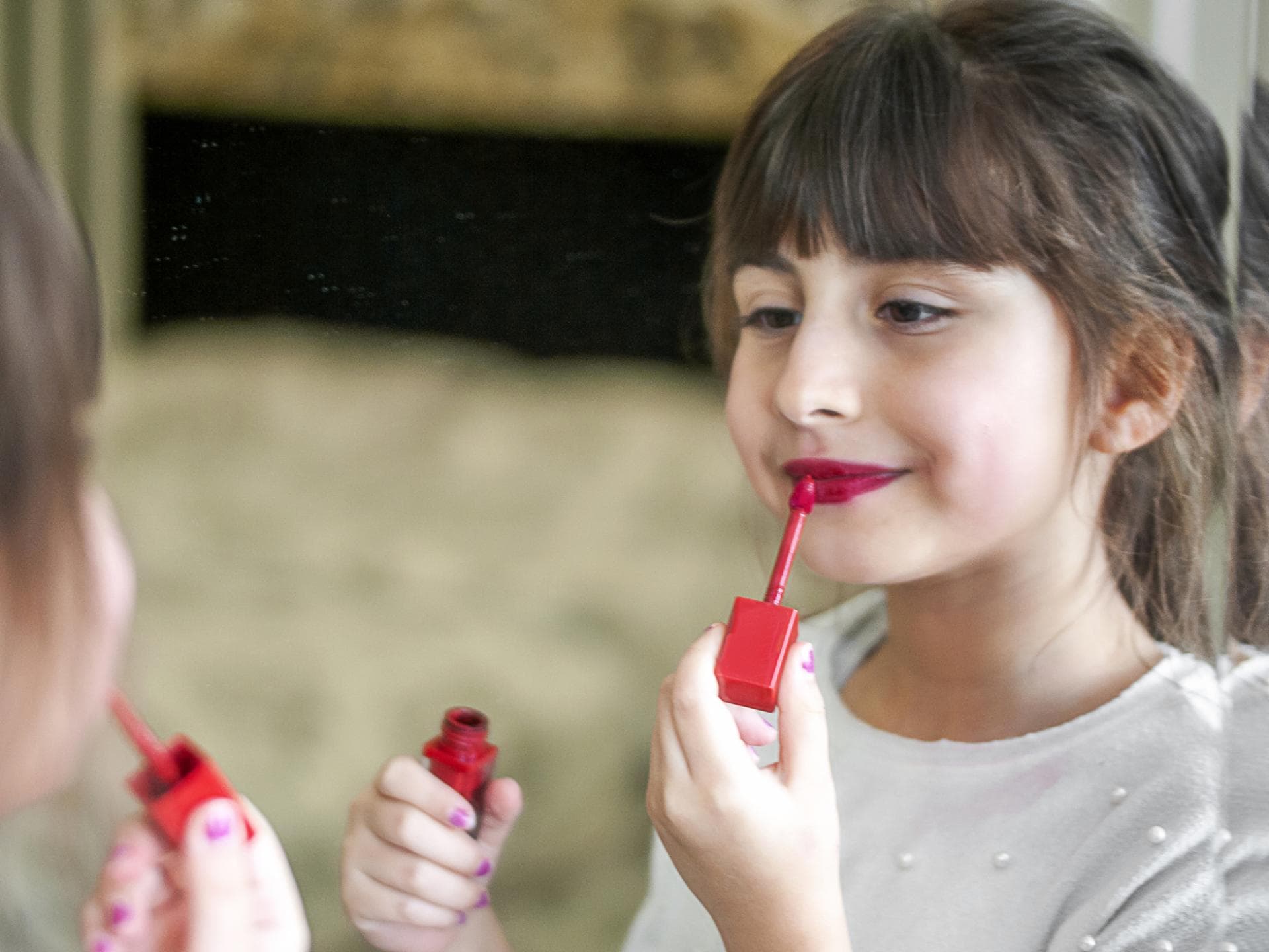 Ein kleines Mädchen, das sich mit Lipgloss schminkt