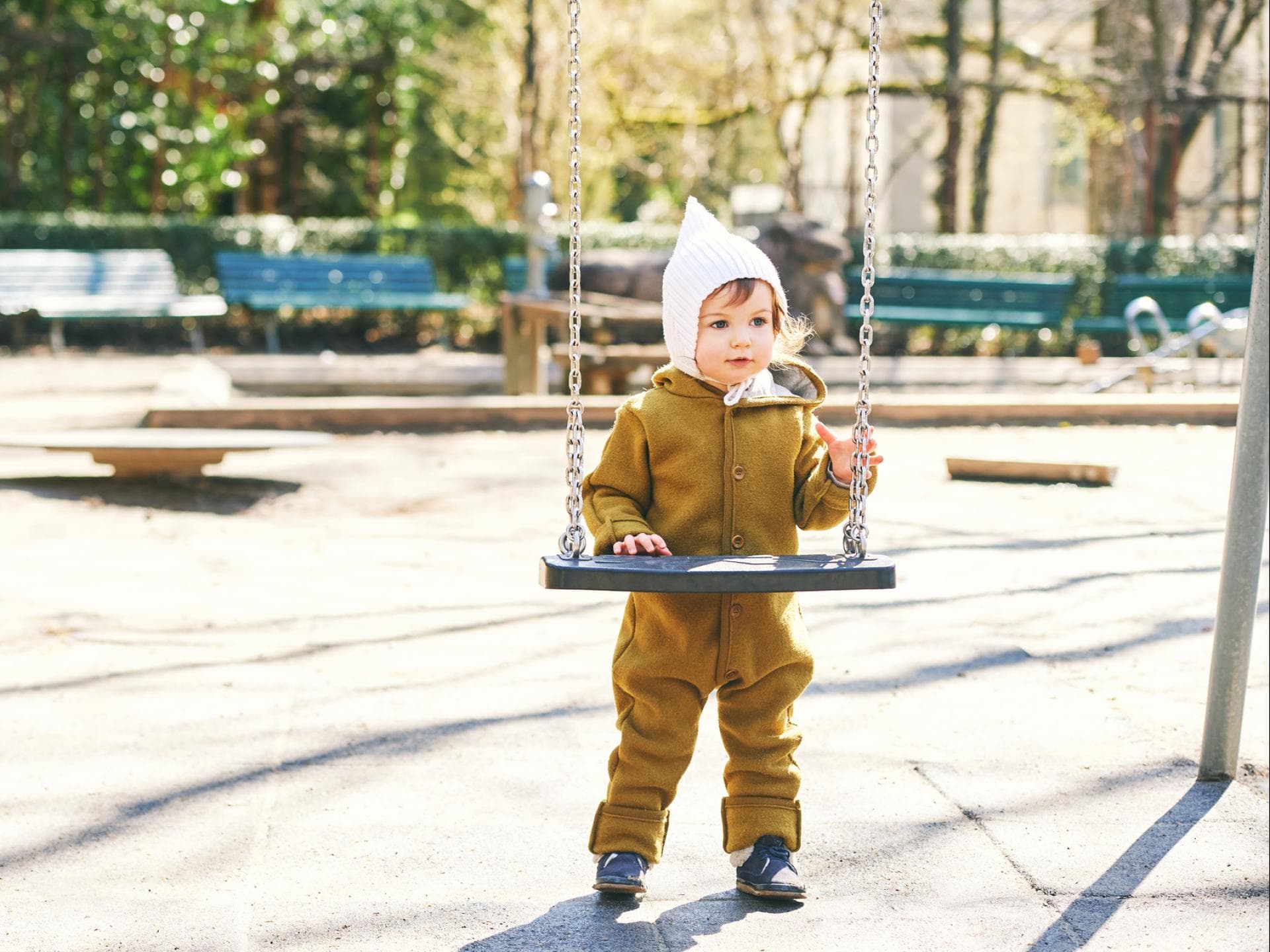 Ein Kleinkind im Wollwalkoverall auf dem Spielplatz