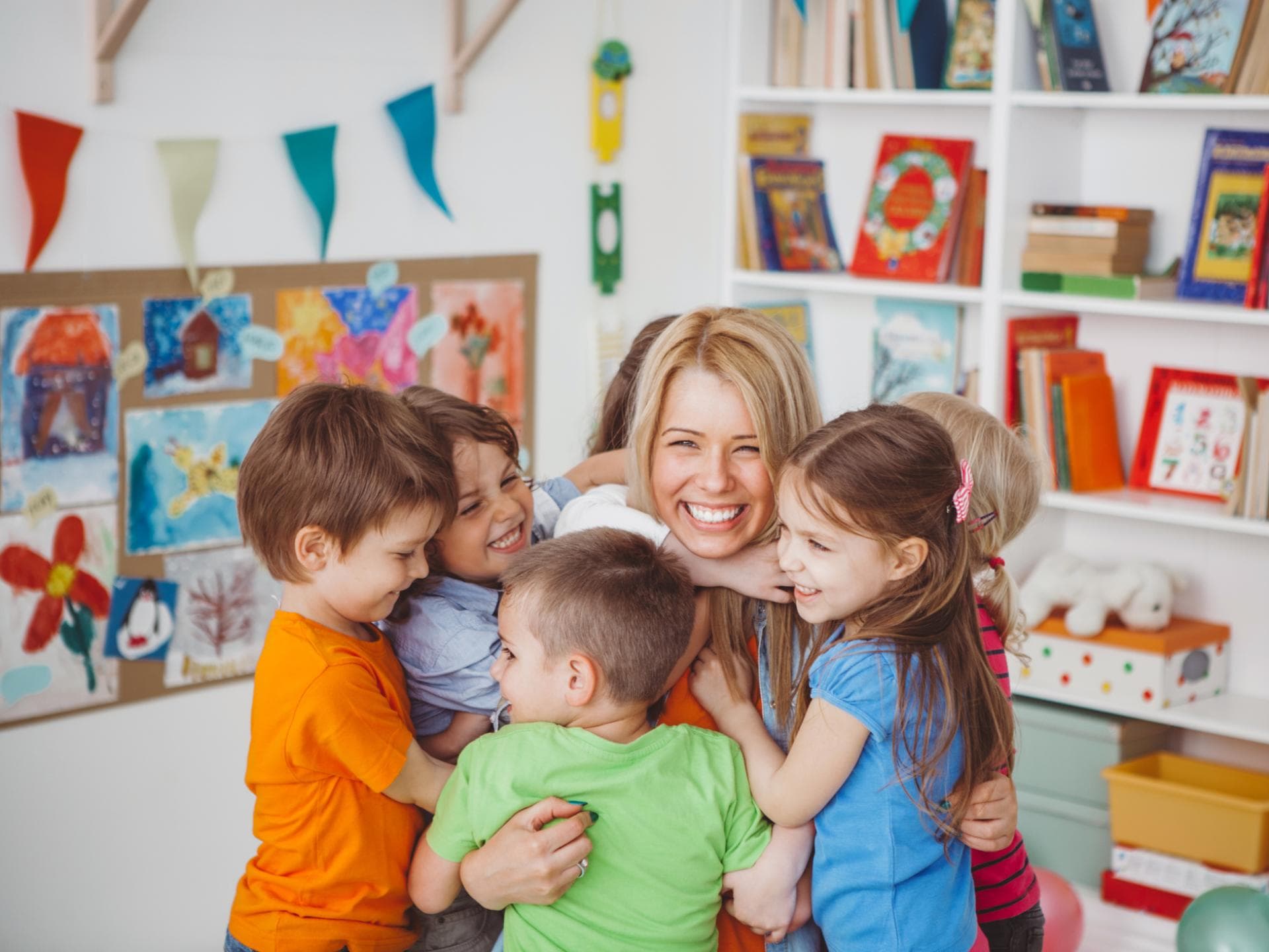 Eine Erzieherin wird herzlich von den Kindern zum Geburtstag umarmt.