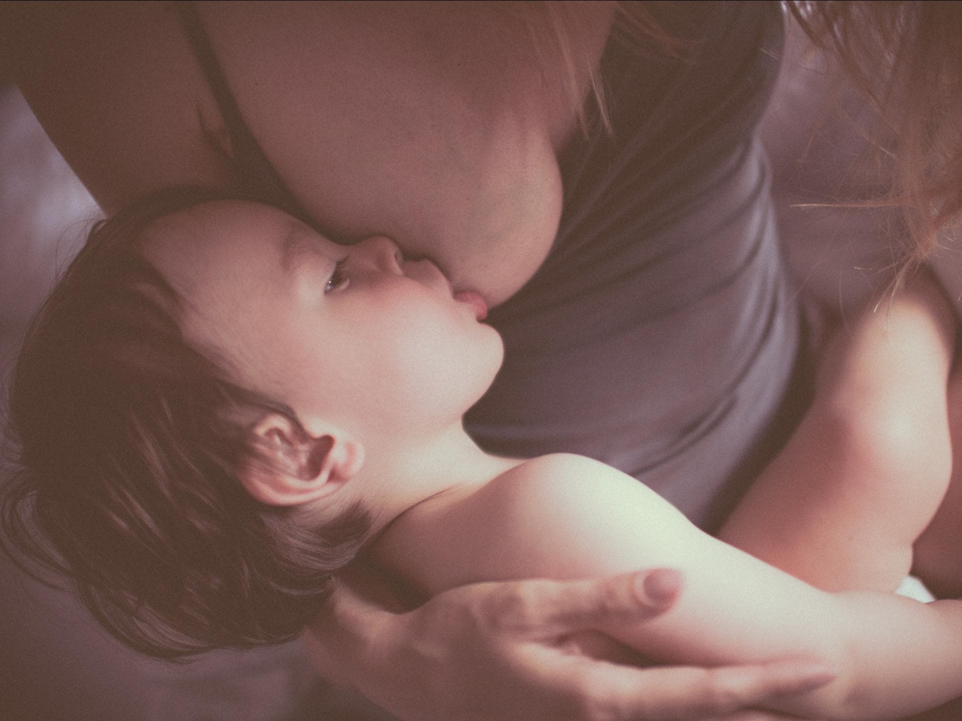 Nachts abstillen ist für viele Mamas und Kinder schwer ... Ein kleines Kind, das von seiner Mutter gestillt wird.