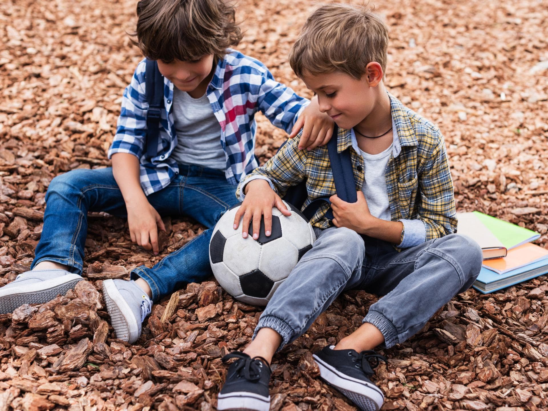 Zwei Jungen mit Fußball und Büchern.