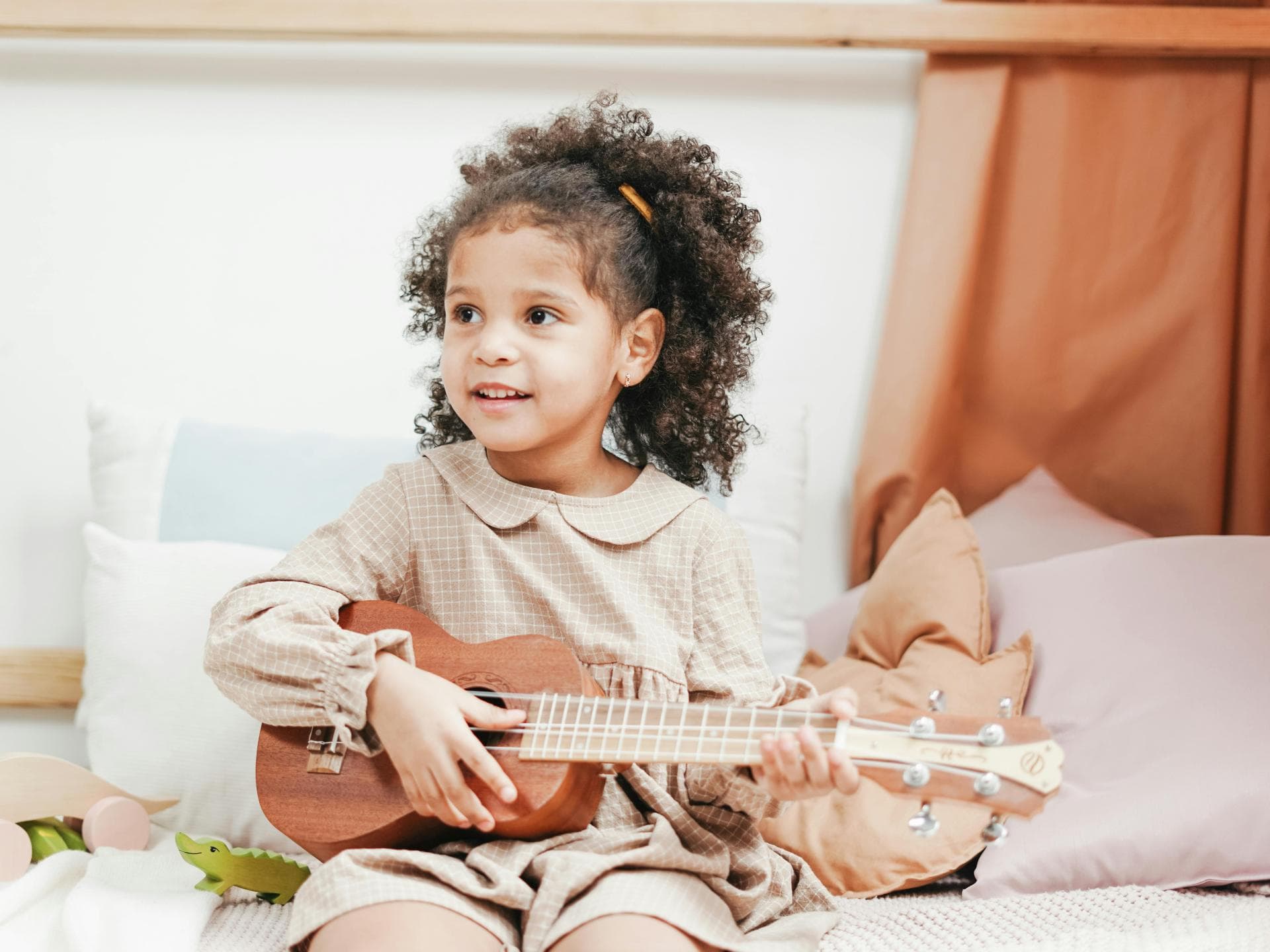 Kinderbücher können die Musikalität stärken. Kleines Mädchen spielt Ukulele.