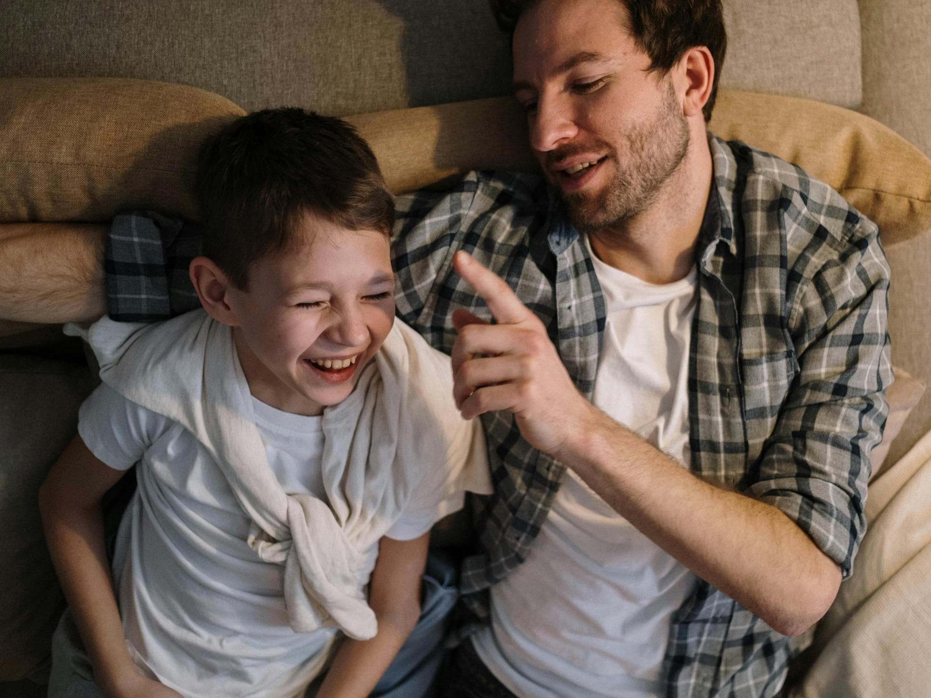 Über Witze lässt es sich am besten gemeinsam lachen. Ein Vater tickt seinen Sohn mit dem Finger an, der bereits zu lachen anfängt.