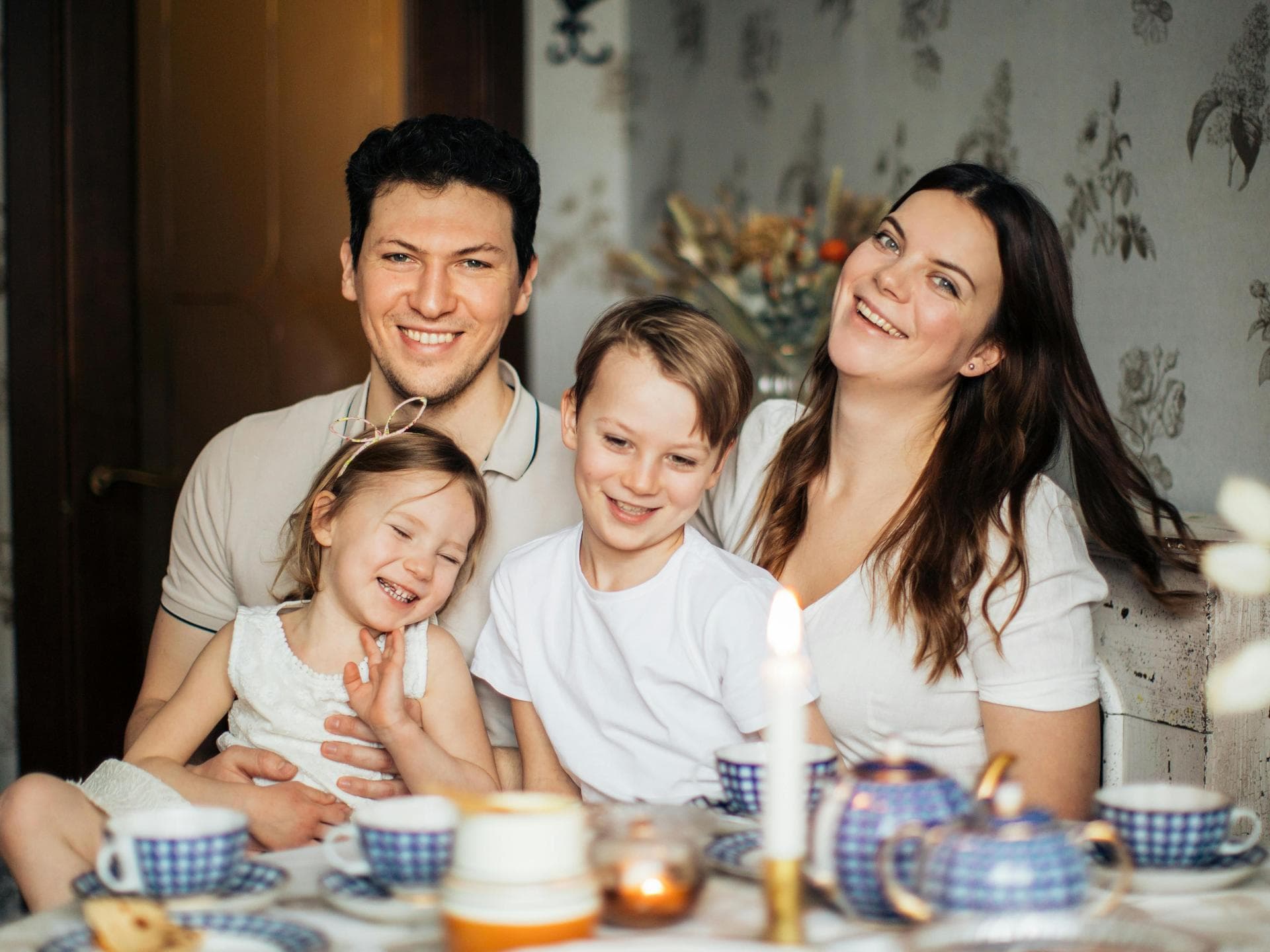 Rasenmäher-Eltern versuchen alle vermeintlichen Probleme ihrer Kinder abzufangen. Eine glückliche, vierköpfige Familie ist abgebildet.
