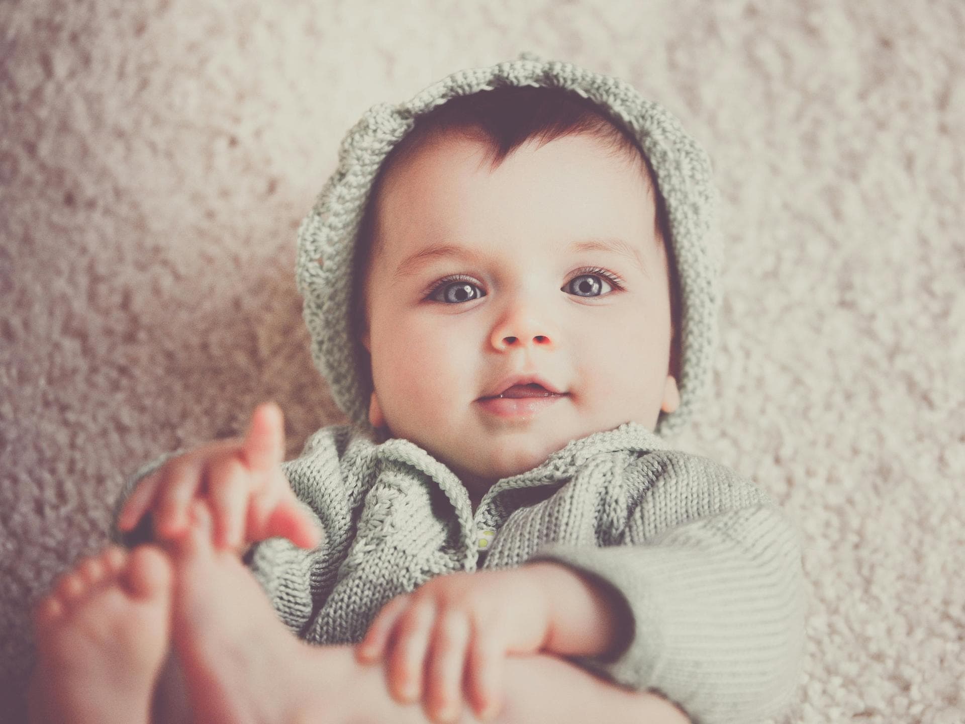 Baby liegt auf dem Rücken und schaut in die Kamera.