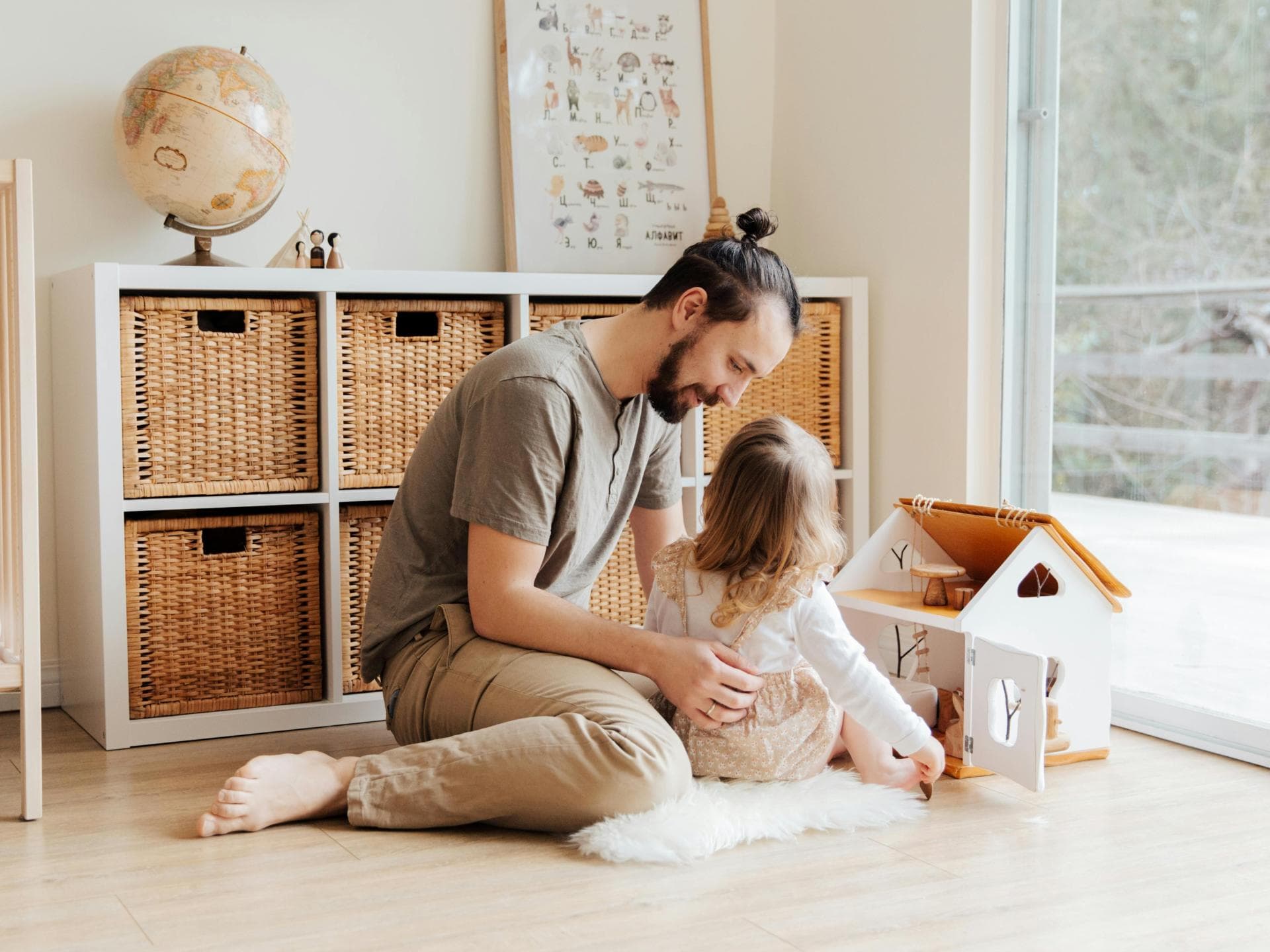 Spielen verbindet und intensiviert die Beziehung zueinander. Ein Vater spielt mit seiner Tochter im Kinderzimmer und umarmt sie dabei.