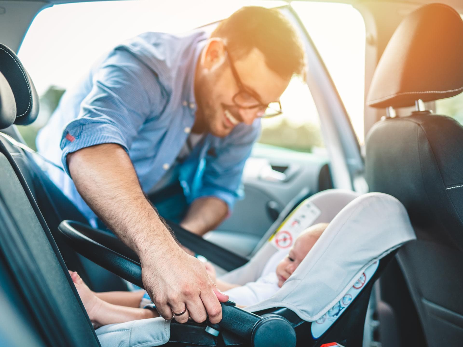 Vater schnallt sein Baby im Auto an.